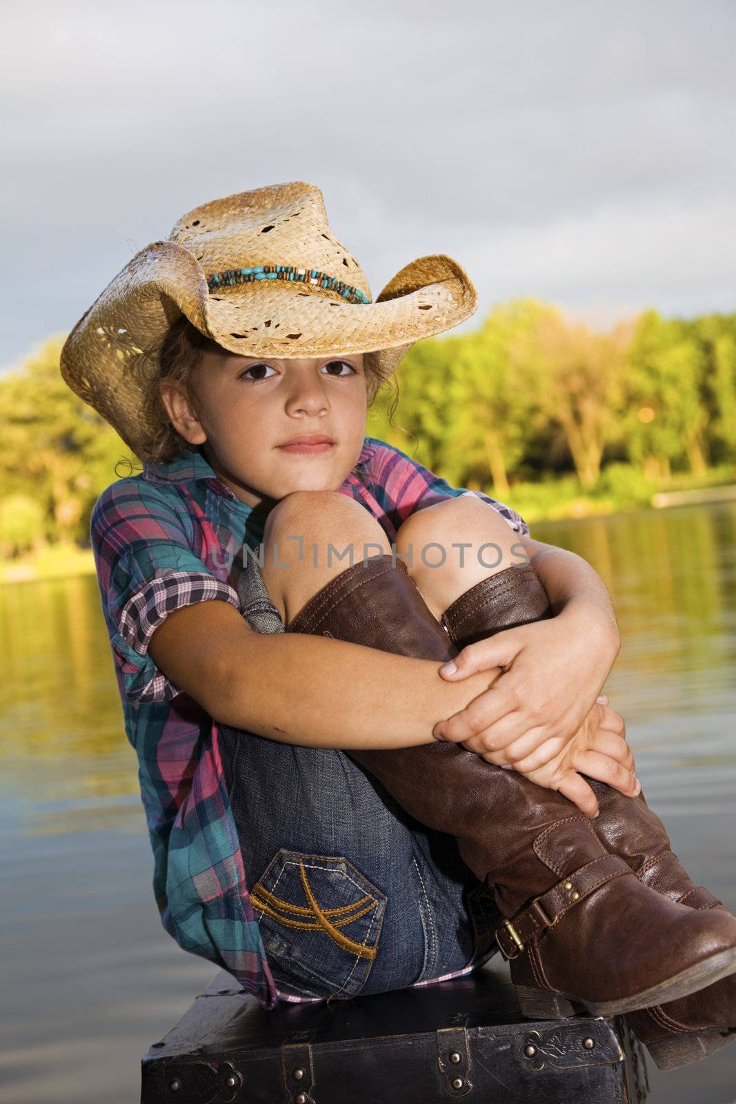 Small girl sitting by the lake