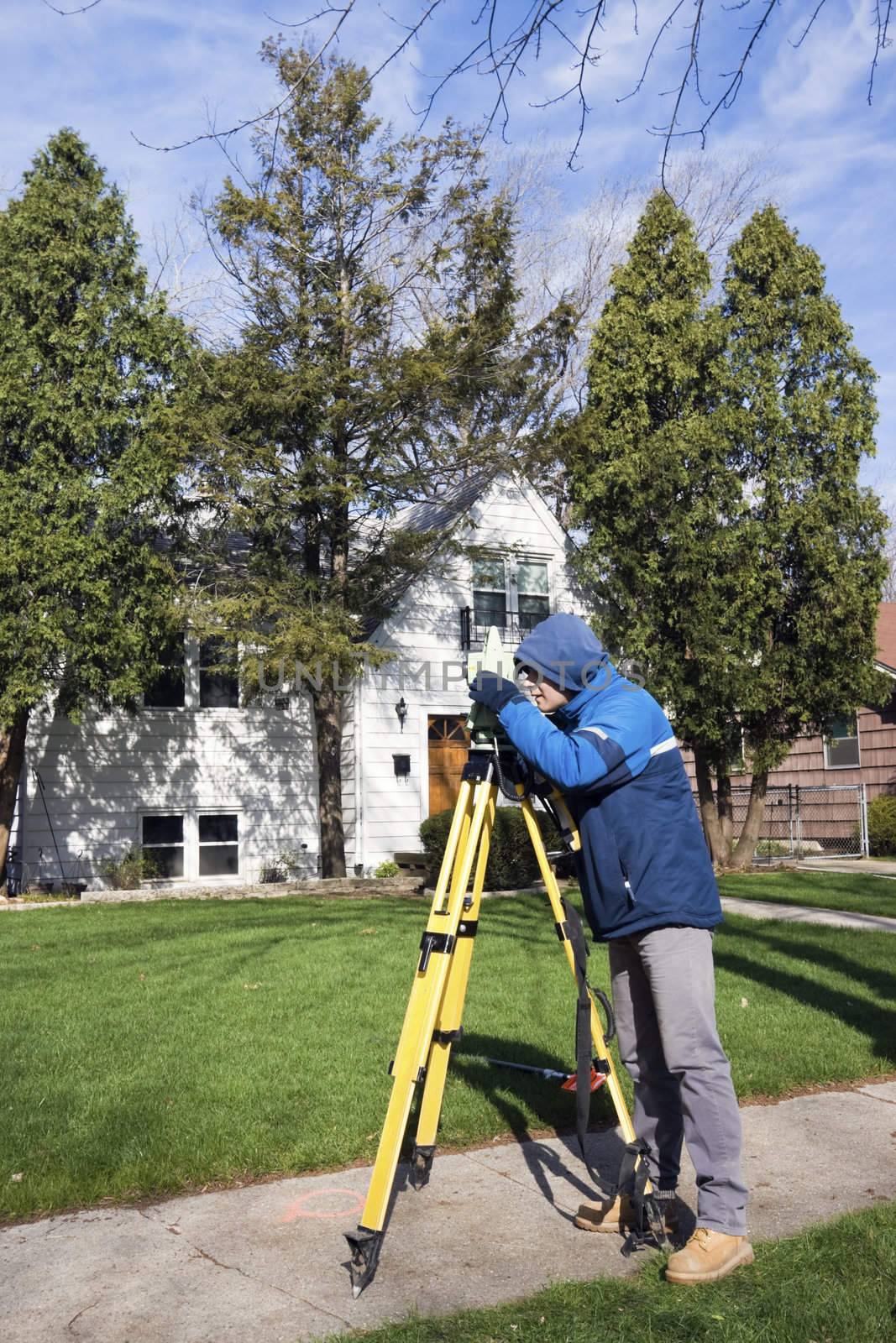 Surveyor working with theodolite in residential area.