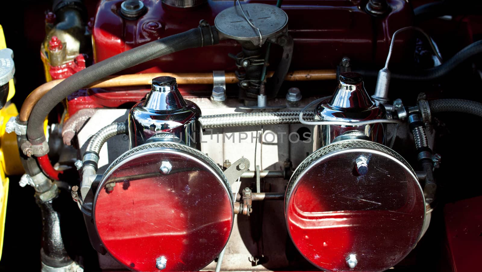 Old vintage car engine with shiny air intakes and piping