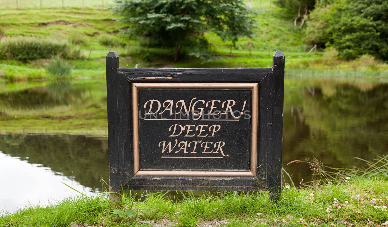 Sign warning of deep water by reflecting pond