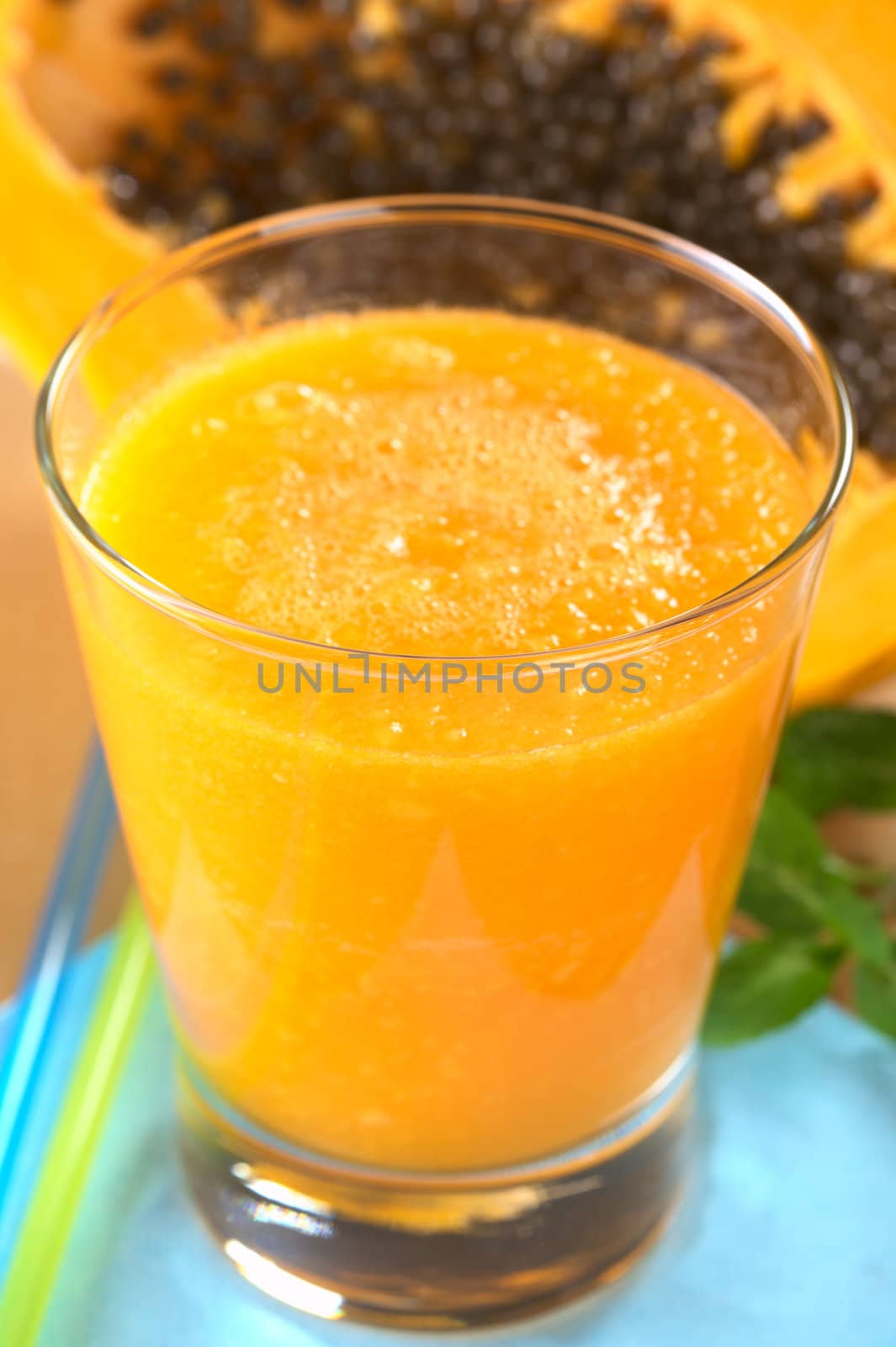 Fresh blended papaya juice with a papaya half in the back (Selective Focus, Focus on the front of the glass rim) 