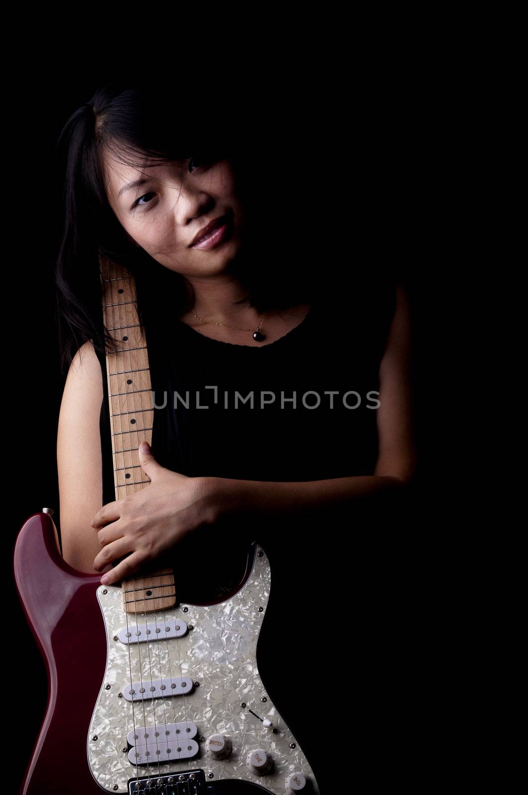 Young woman with electronic guitar,  isolated on black background.