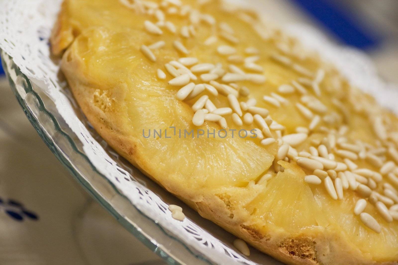 Close view of a homemade pineapple cake decorated with pine nuts.
