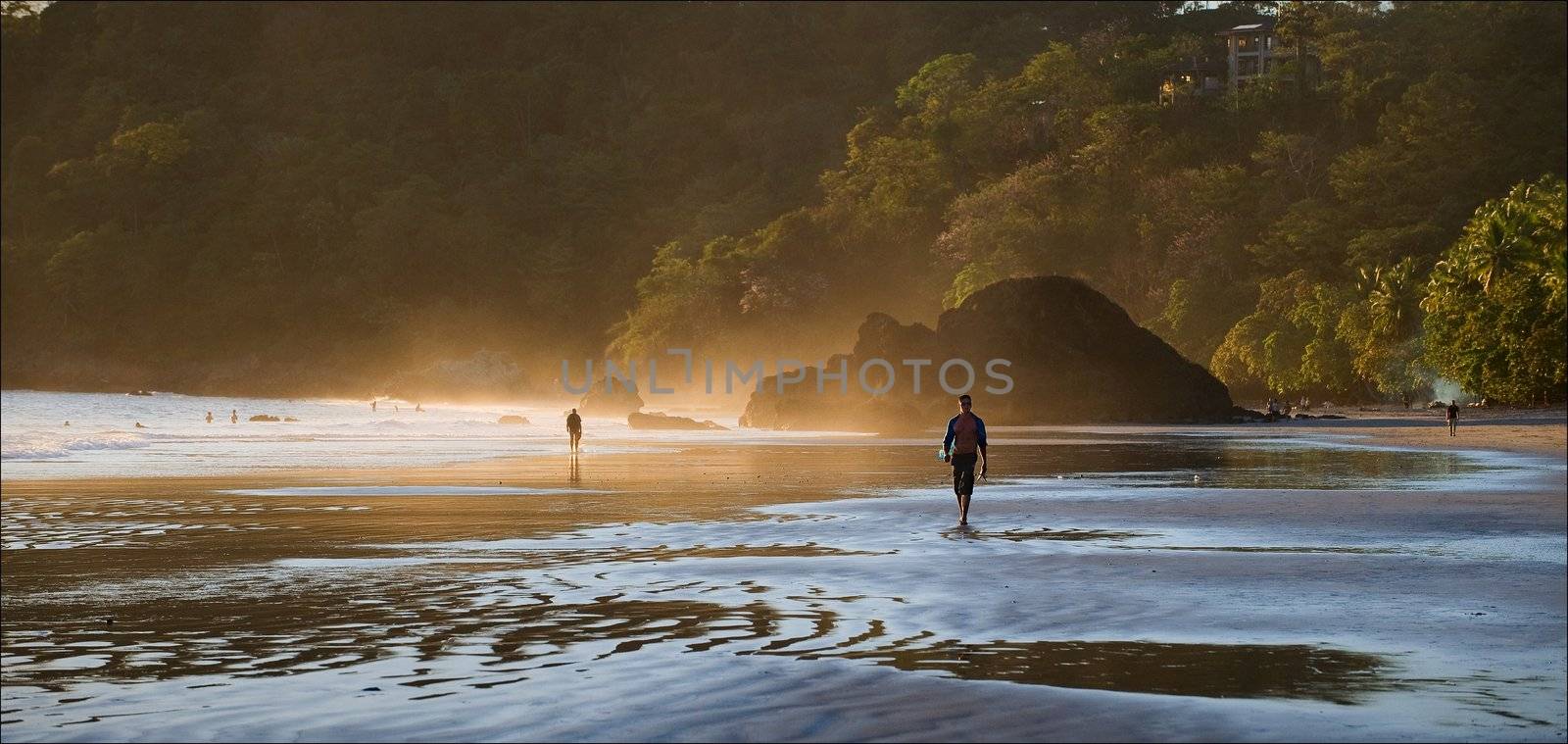 Dawn at coast of Pacific ocean. Wet sand, foggy a smoke and the walking person.