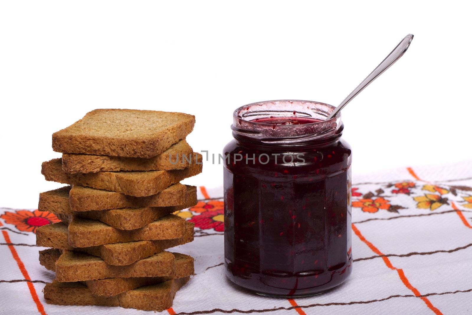 Close view of a toasted bread with berry jam jar isolated on a white background.