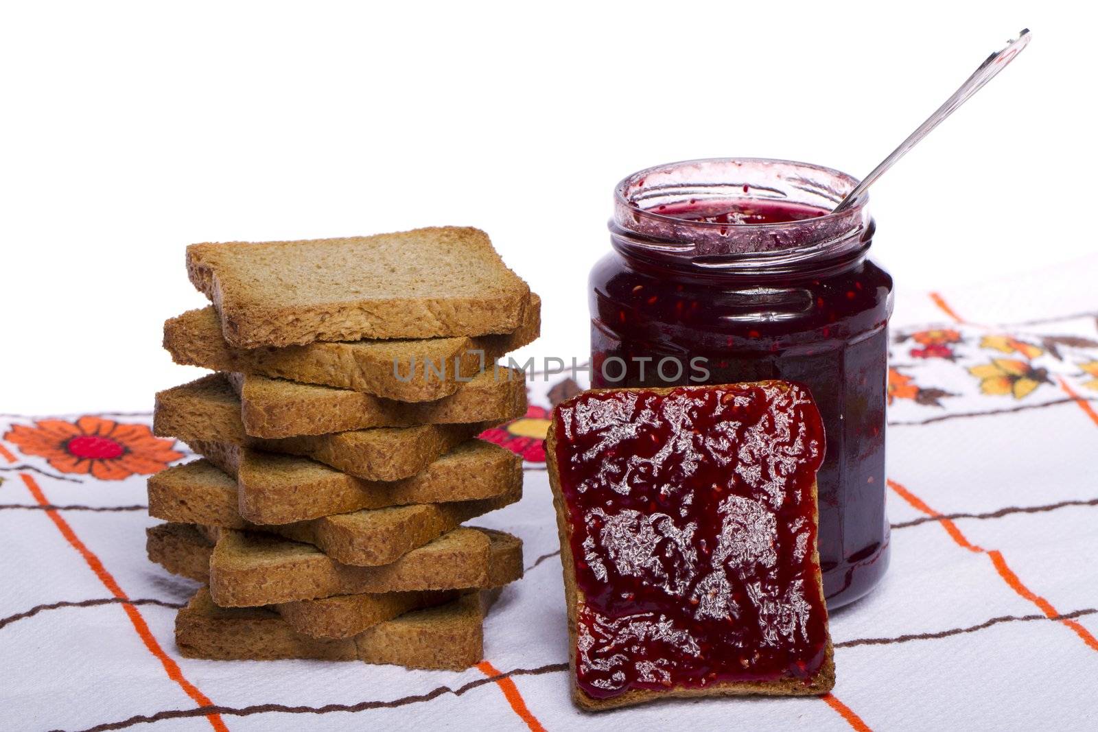 Close view of a toasted bread with berry jam jar isolated on a white background.