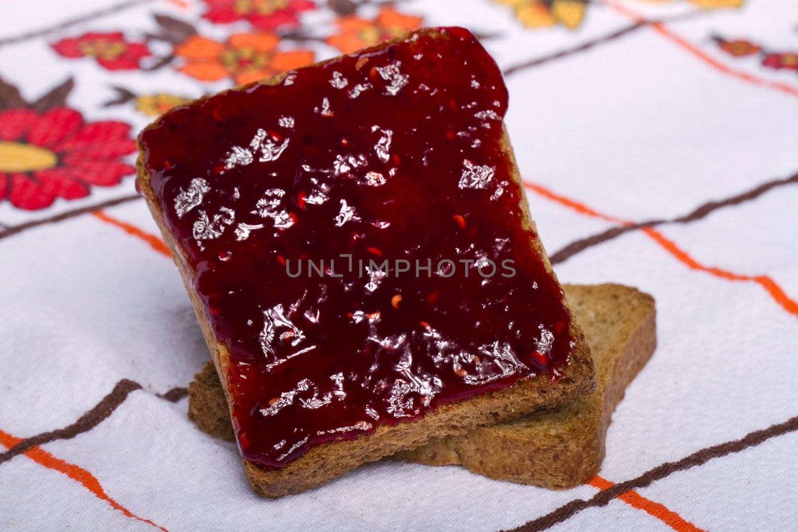 Close view of a toasted bread with berry jam isolated on a white background.