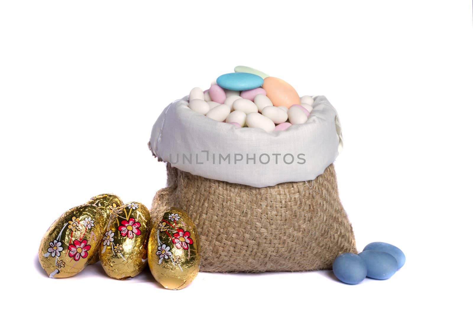 Close up view of sweet almonds and chocolate eggs inside a sack isolated on a white background.