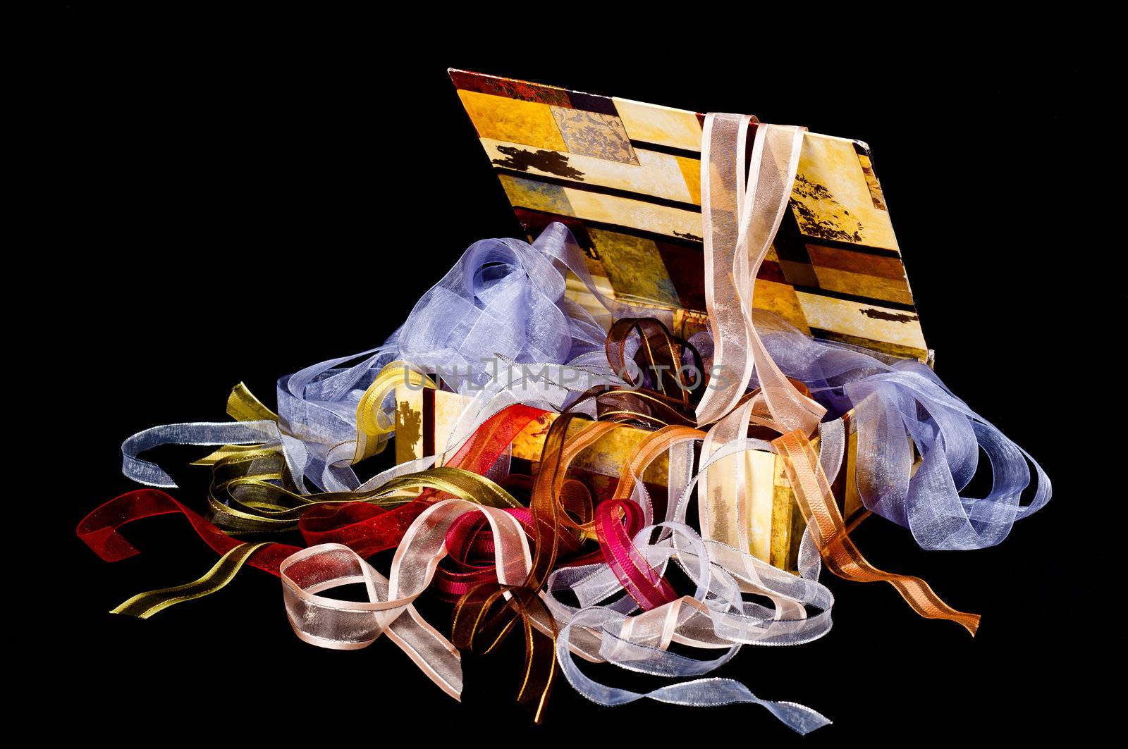 Beautiful box overflowing with colorful ribbons on a black background