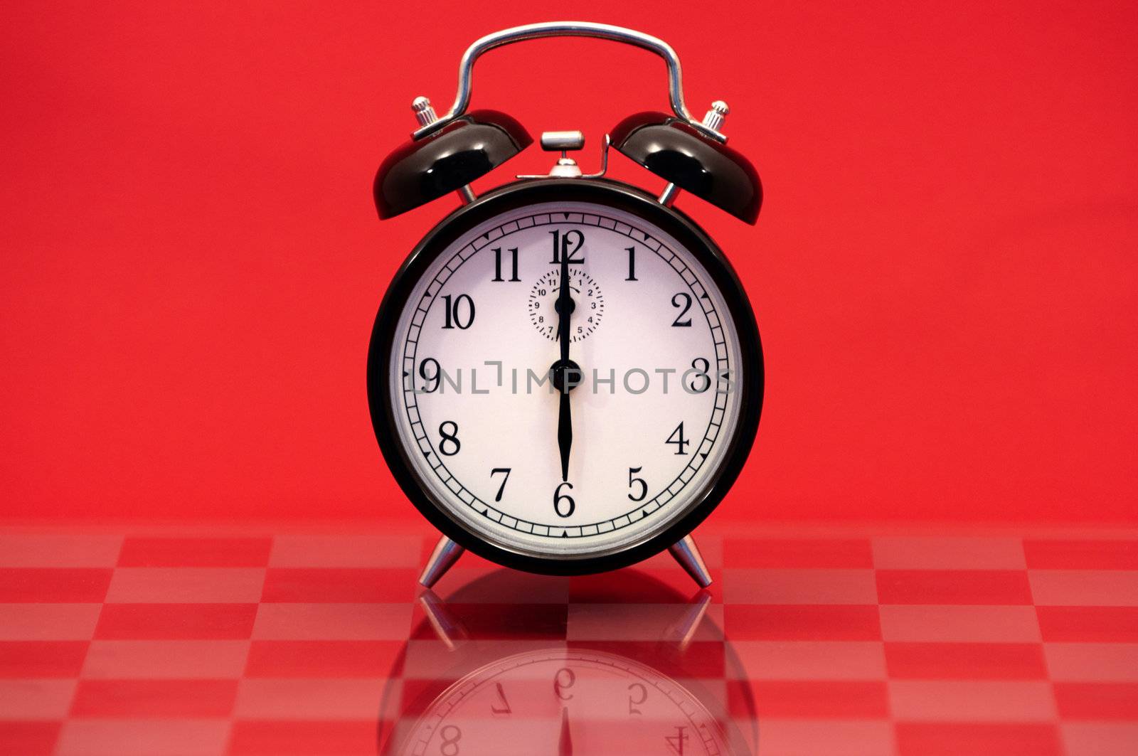 Vintage Alarm Clock Showing 6 O'Clock Isolated on a Red Background.