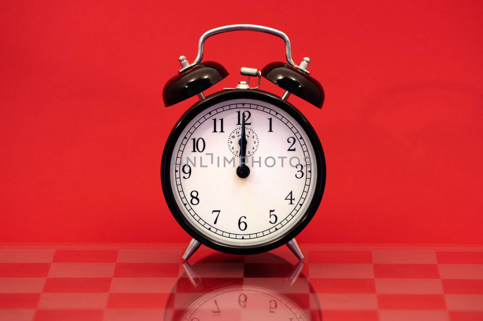 Vintage Alarm Clock Showing 12 O'Clock Isolated on a Red Background.