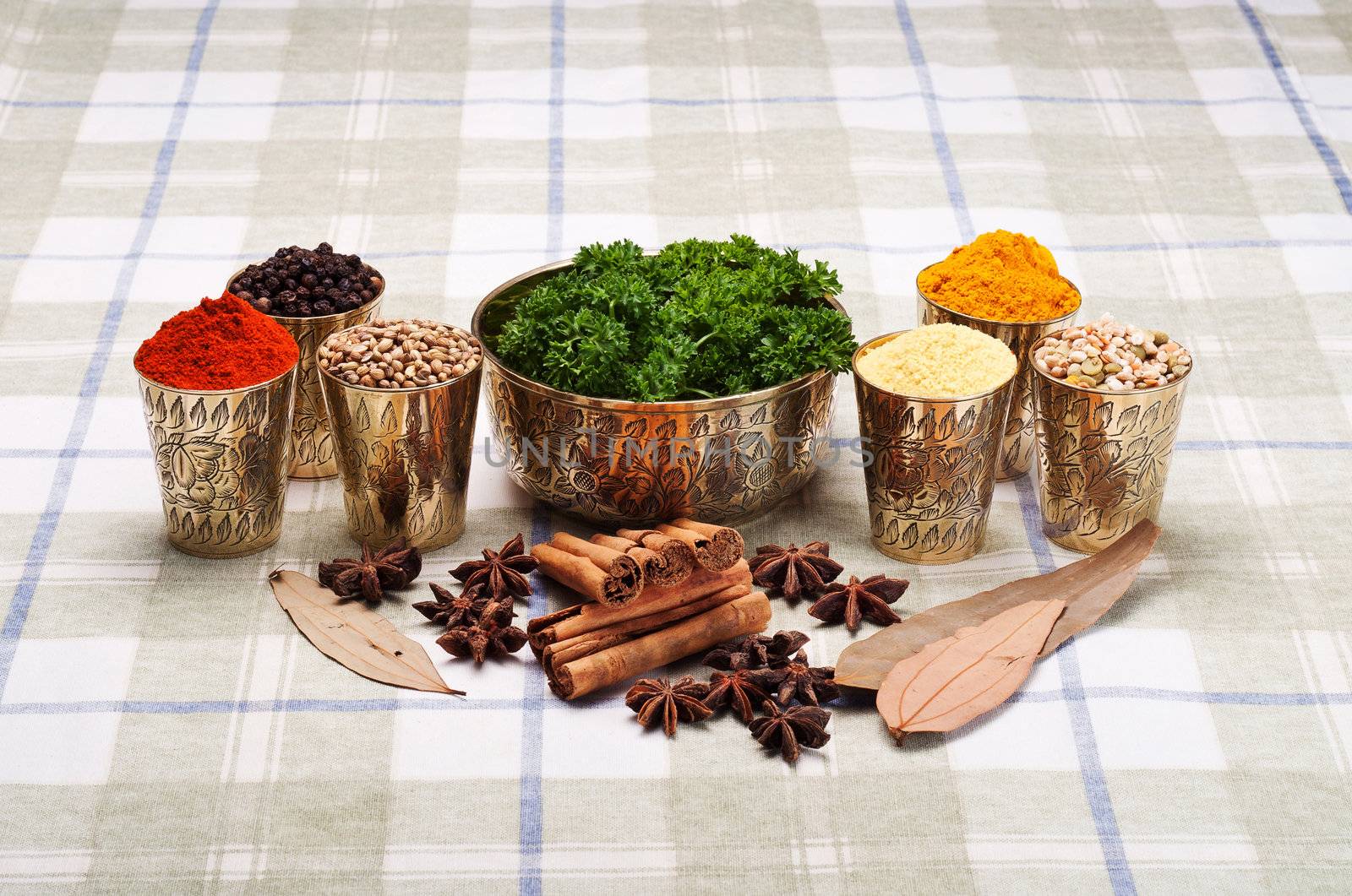 Colorful arrangement of Indian spices in brass containers with parsley