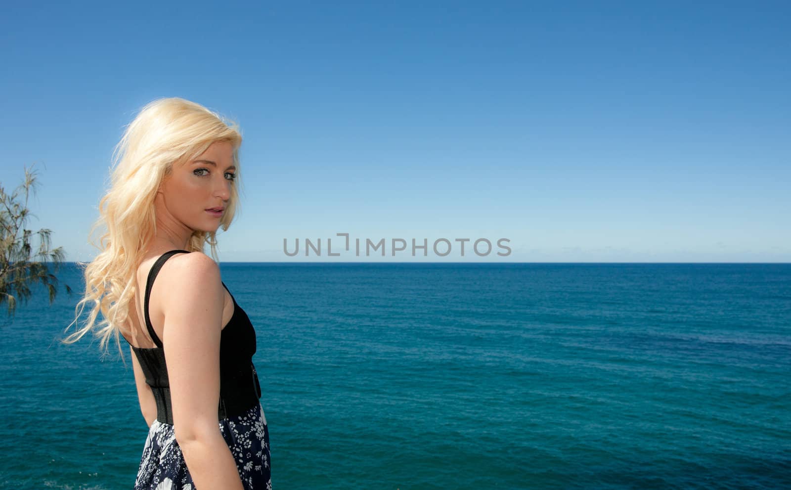 beautiful young woman looks over the ocean 