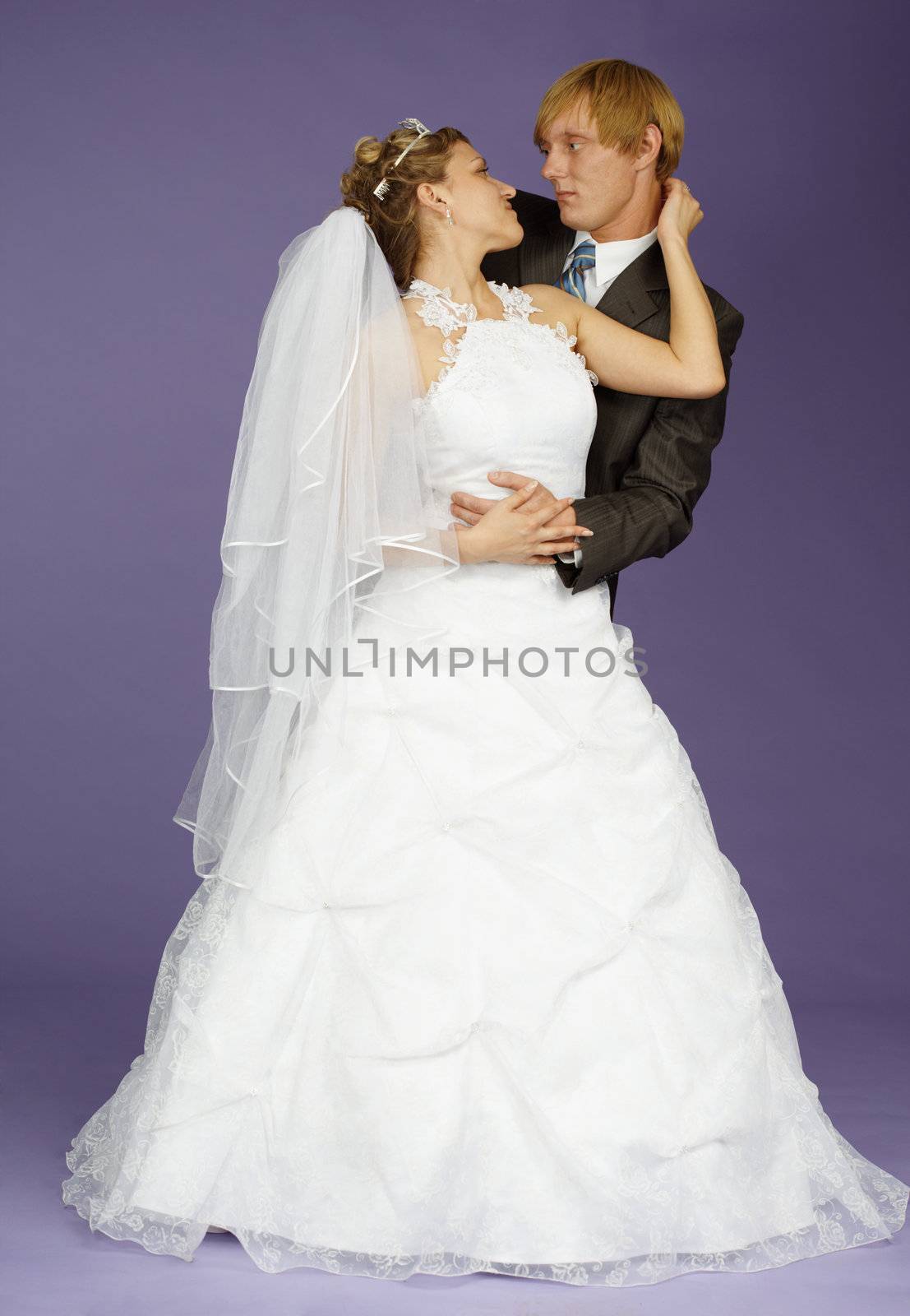 The bride and groom pose on studio