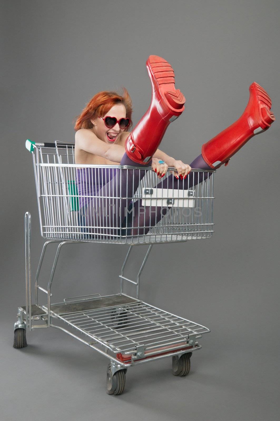 Beautiful excited red woman riding shopping cart