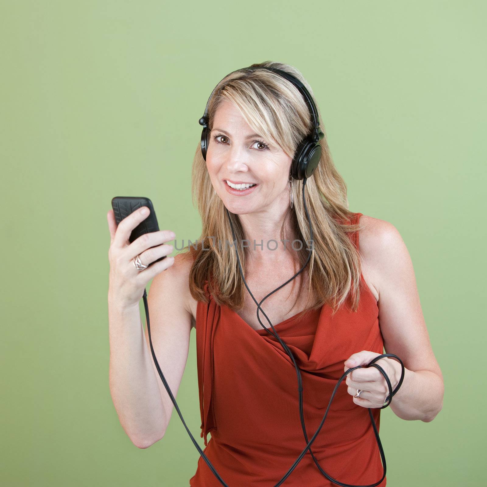 Middle-aged woman listens to music player over green background
