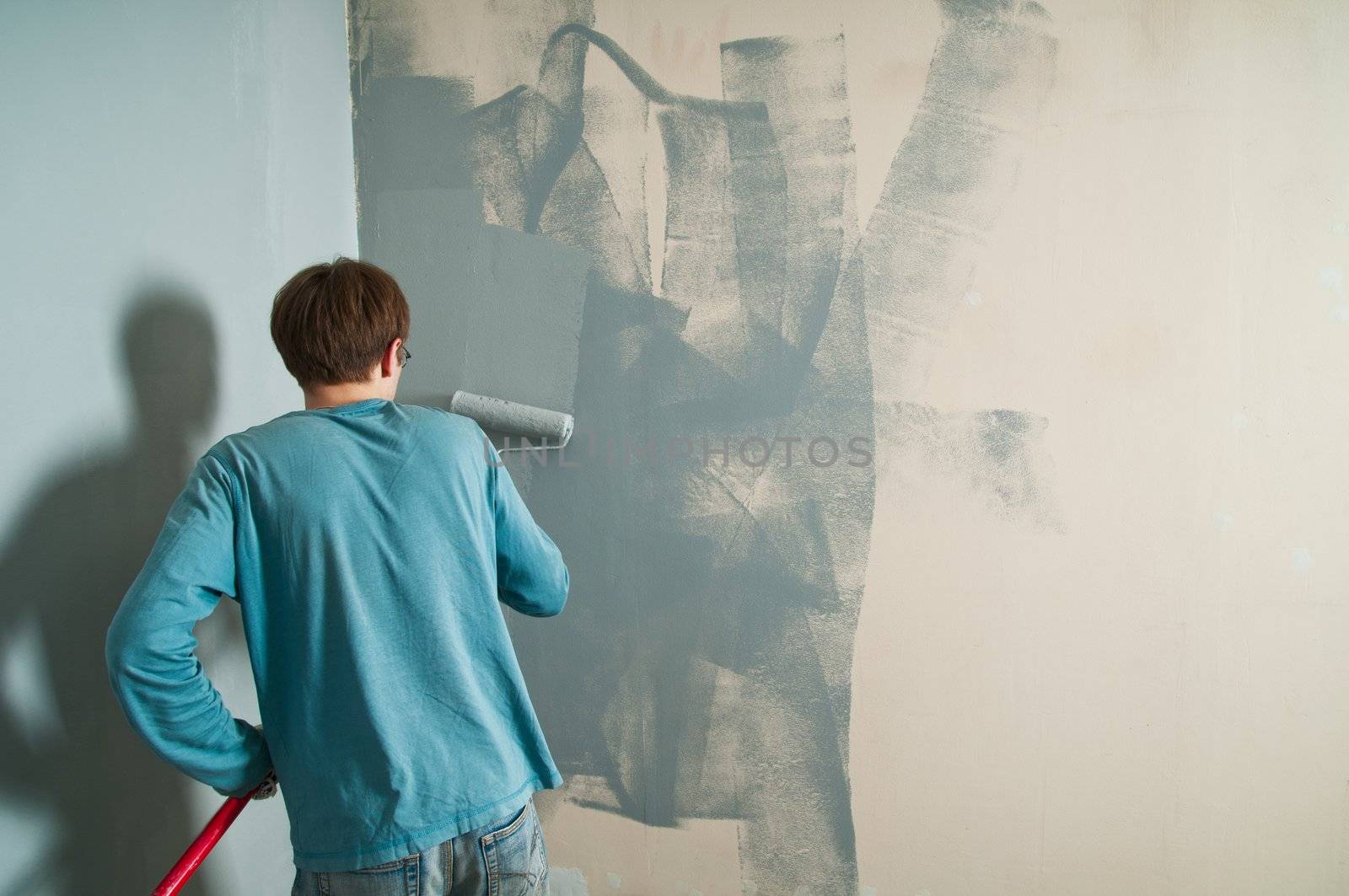 Young man with brush painting the wall