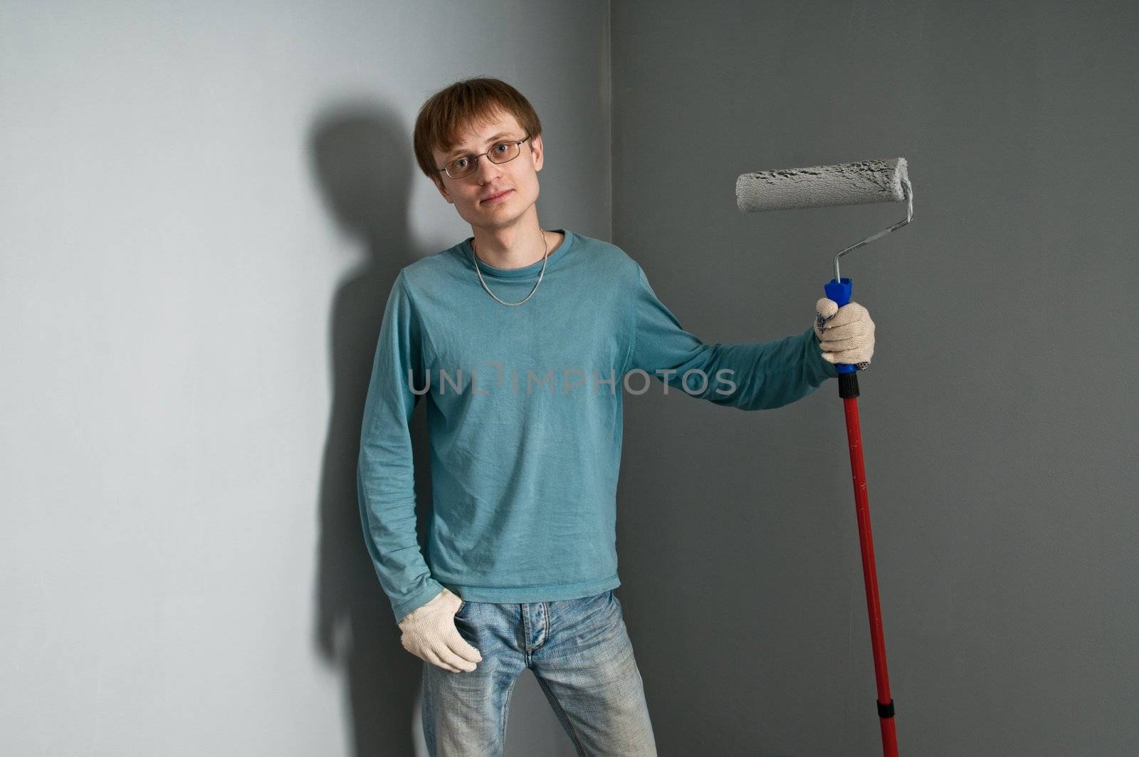 Young man with brush posing against just painted wall