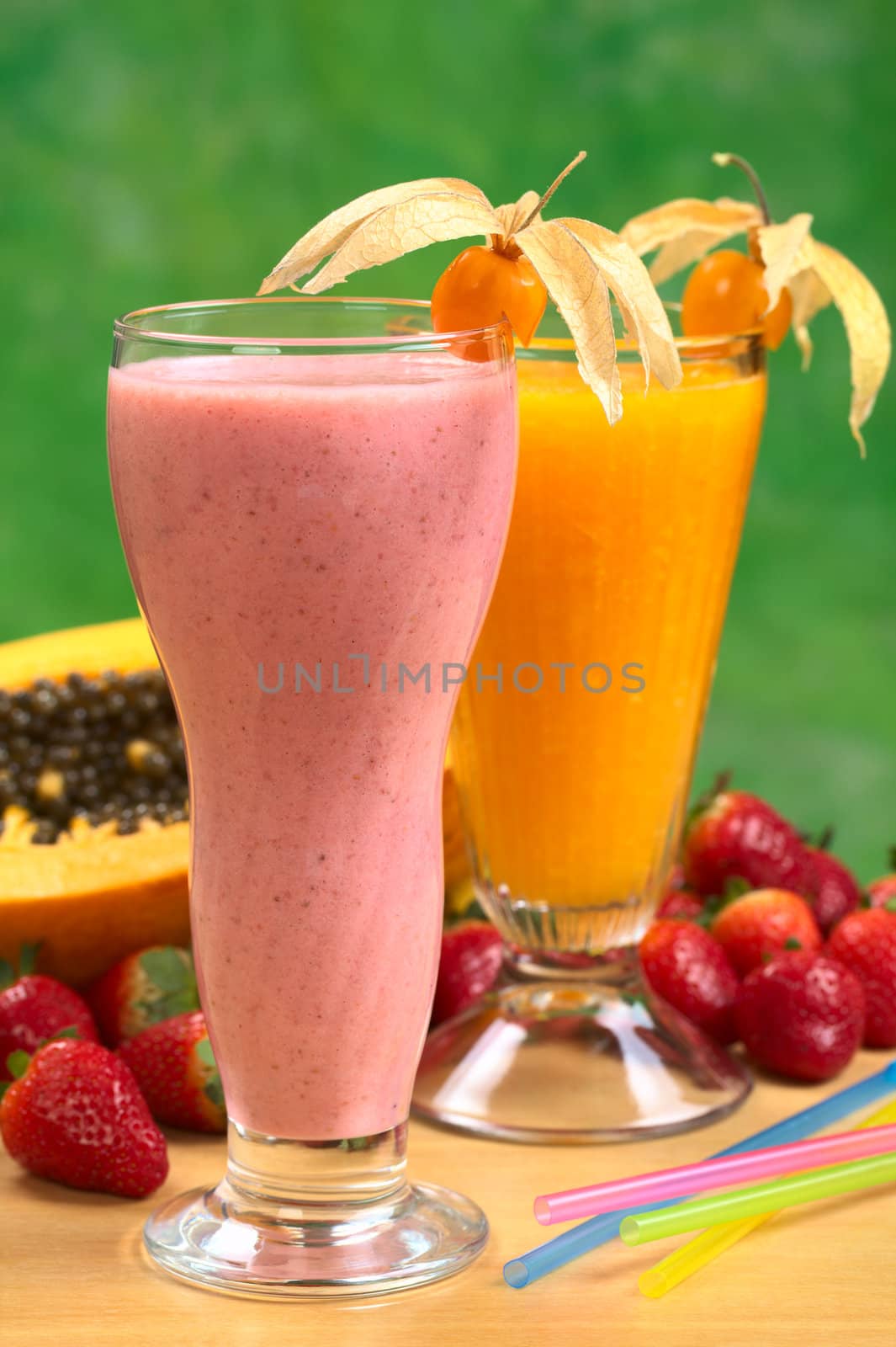 Strawberry milkshake and papaya juice garnished with physalis (Selective Focus, Focus on the physalis on the strawberry milkshake) 