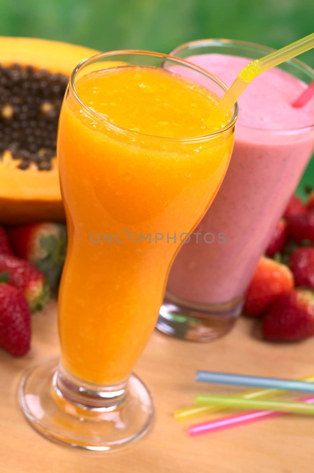 Papaya juice and strawberry milkshake with straws (Selective Focus, Focus on the front rim of the glass and the straw in the papaya juice)