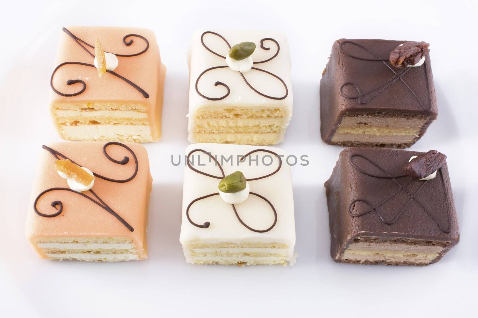 Close up of six petits fours on white plate.