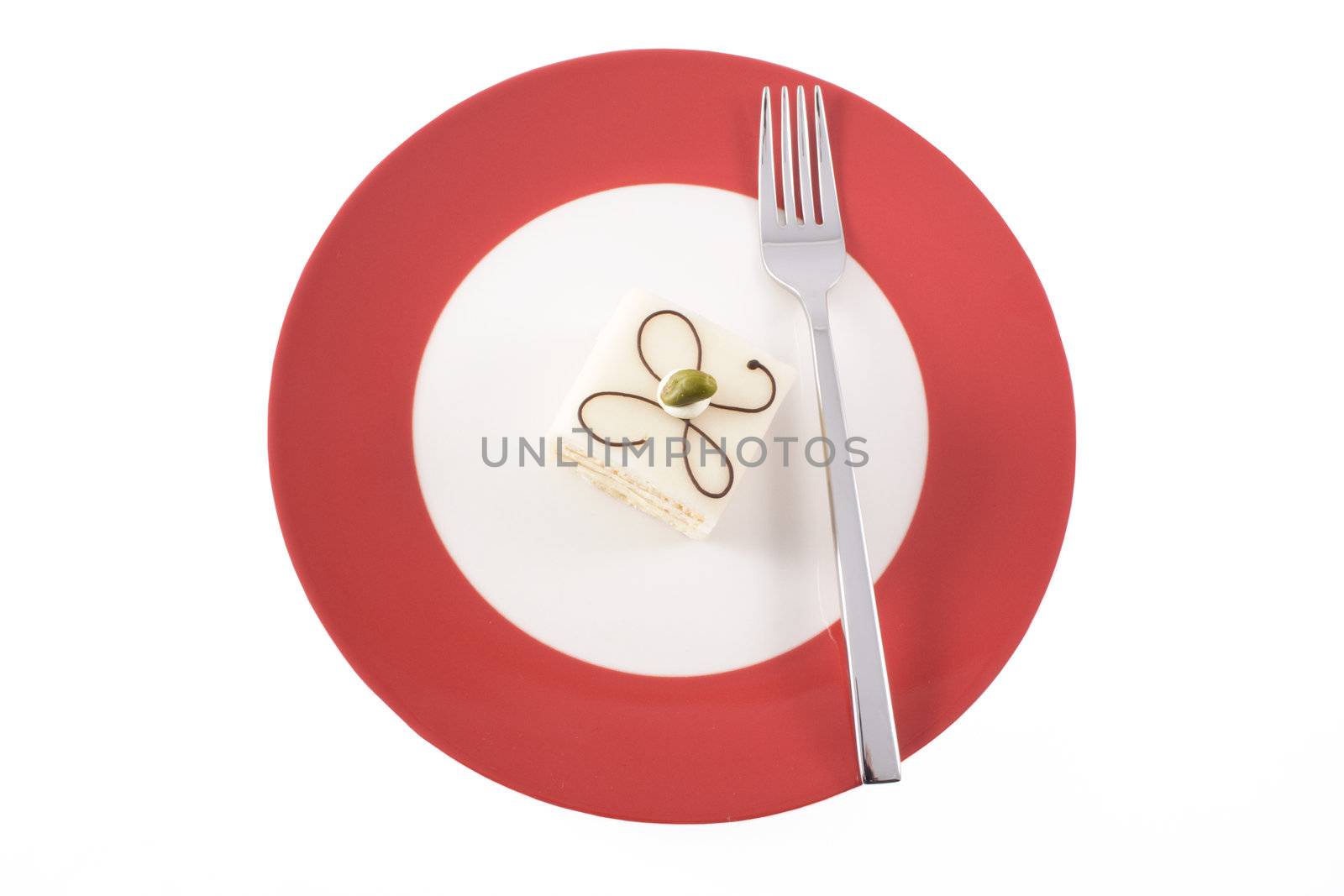 Petit four on red plate with fork.  The photo is from directly above and is isolated on a white background