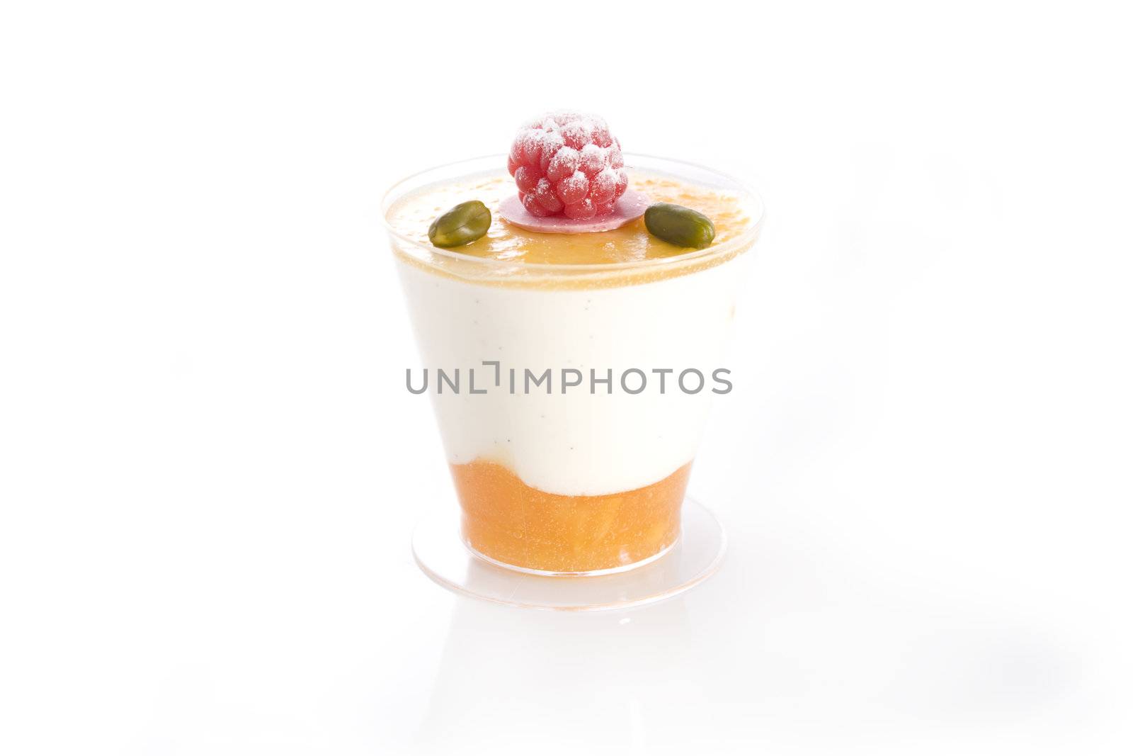 Isolated shot of Vanilla and mango mousse with raspberry and pistachio topping.