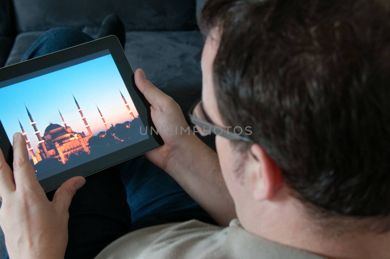 Middle-aged man sitting comfortably on a sofa and checking a digital tablet pc