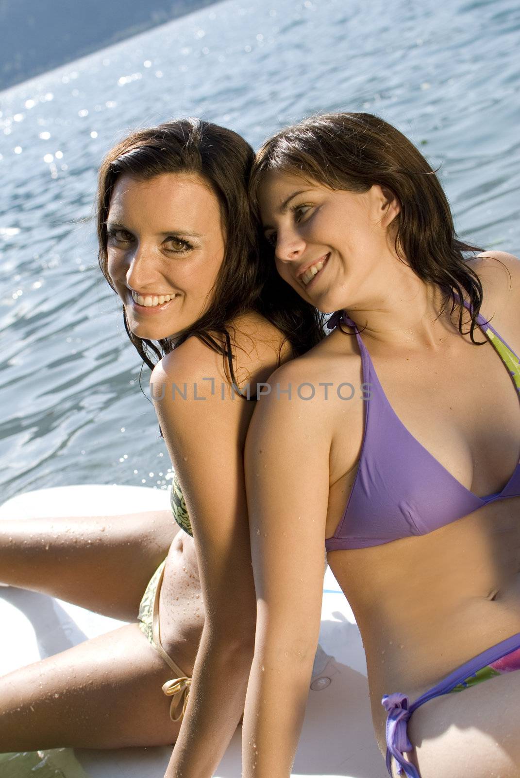 Girls having fun and relaxing on surfboard at the lake of Zell am See, Austria