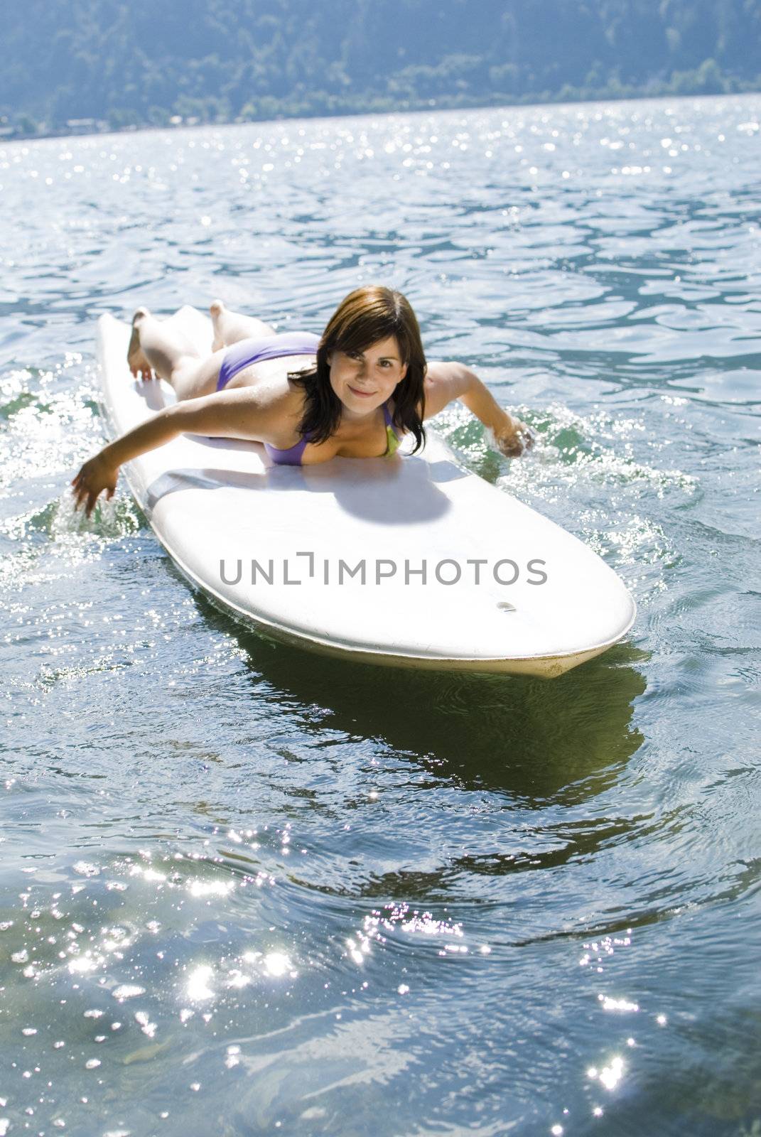Girl relaxing on surfboard at the lake of Zell am See, Austria