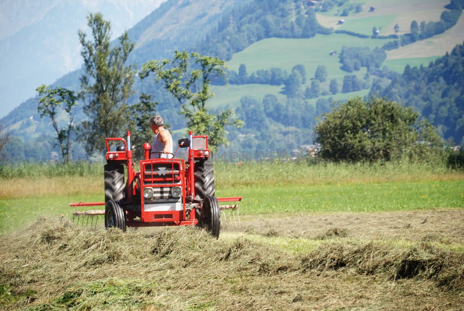 Tractor plowing in front of mountains in austrian farm