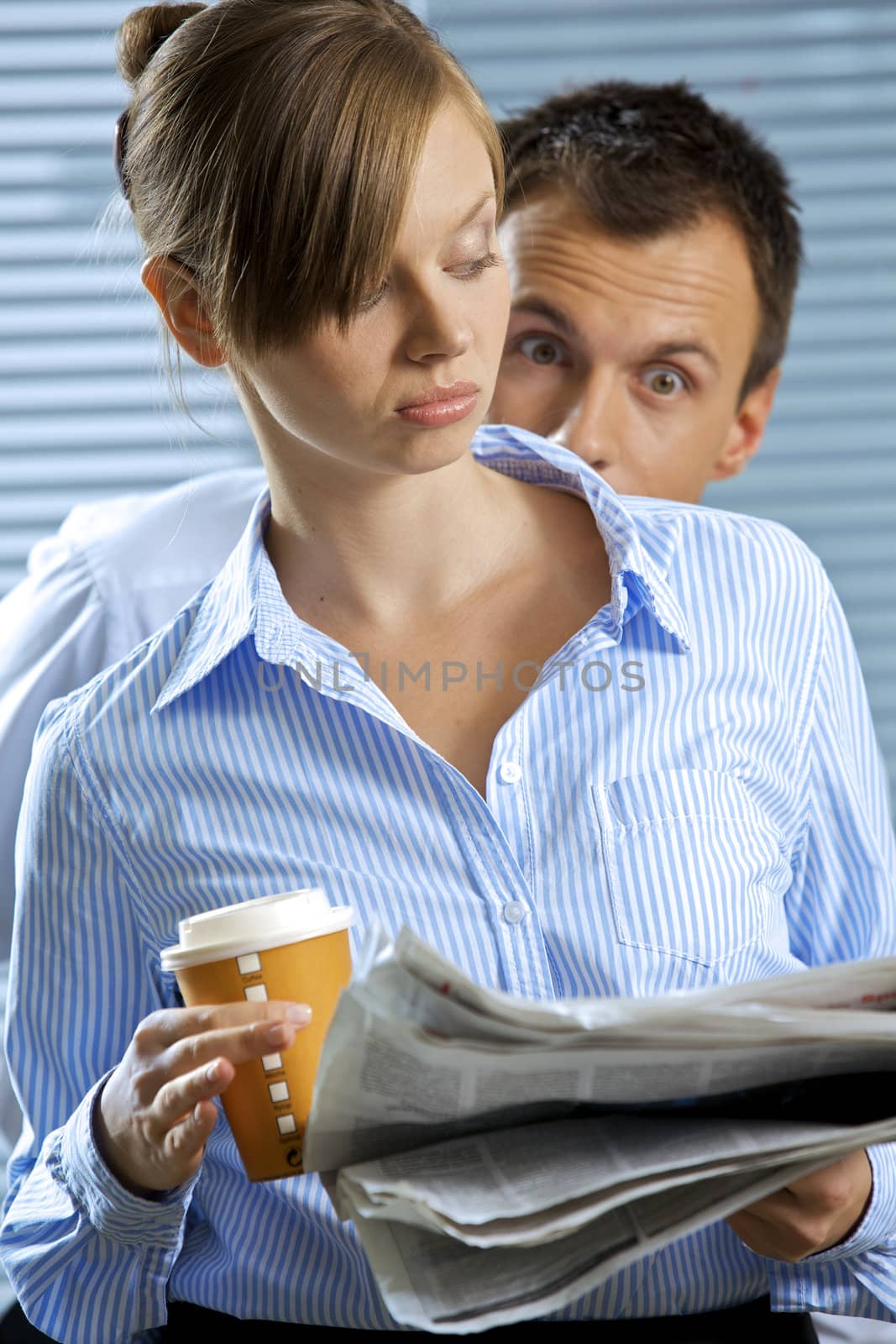 Businesswoman holding glass of coffee and newspaper, businessman staring
