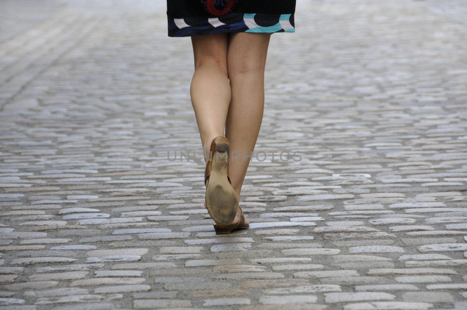 Woman walking on cobbled pavement by fahrner