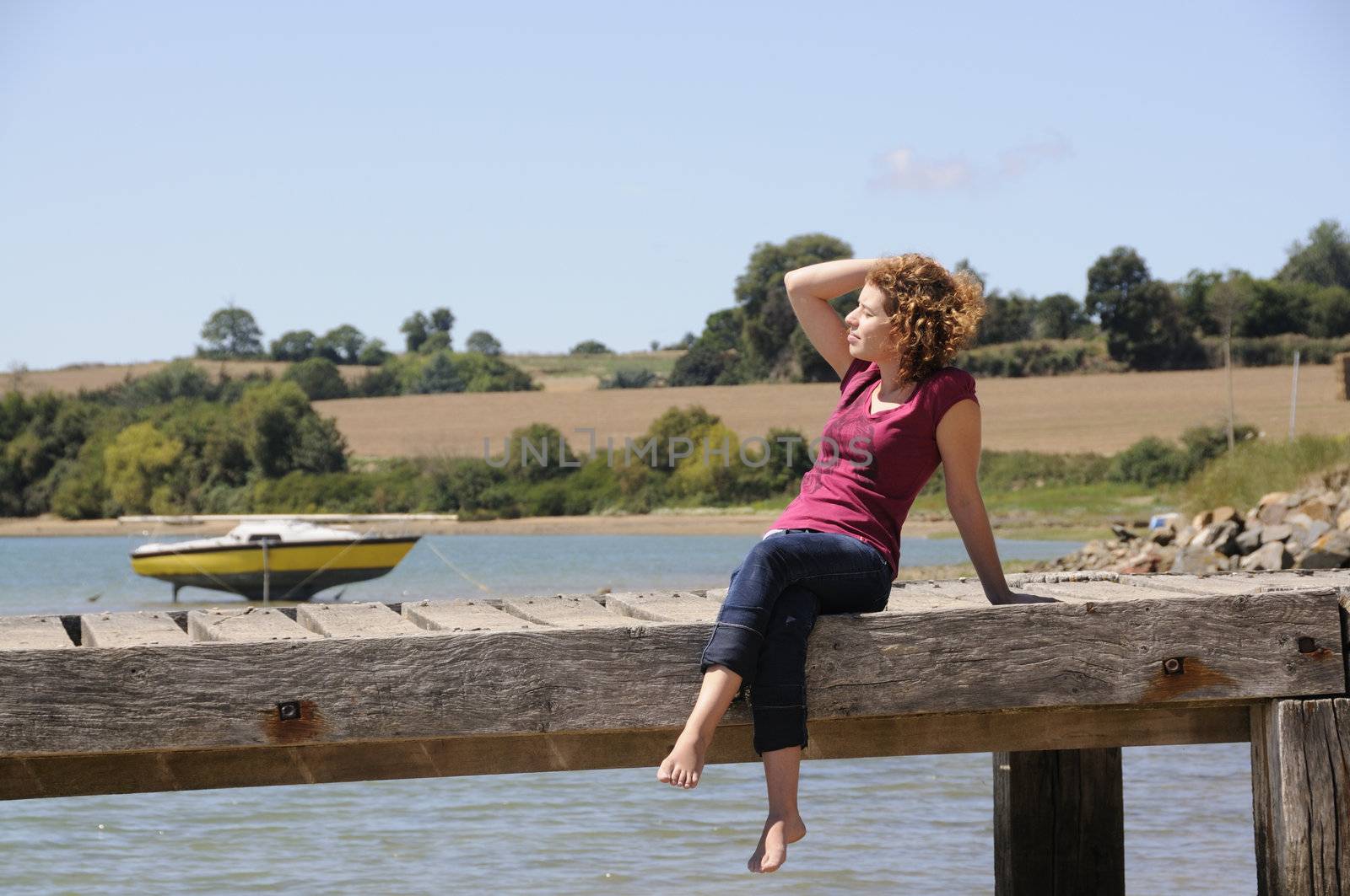 Pretty girl sitting and relaxing on landing stage in Brittany, France on a sunny day.