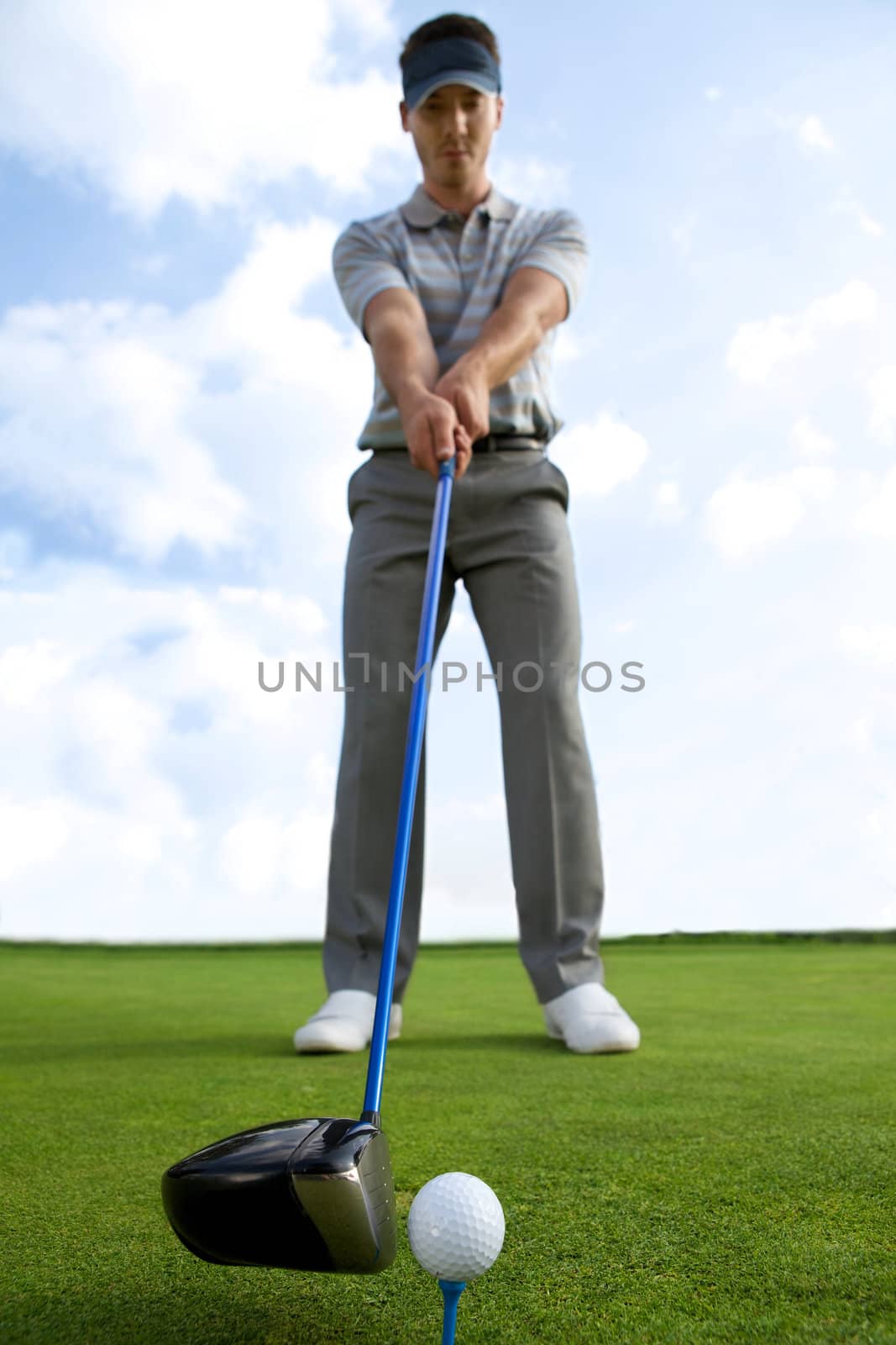 Man about to strike golf ball, low angle view