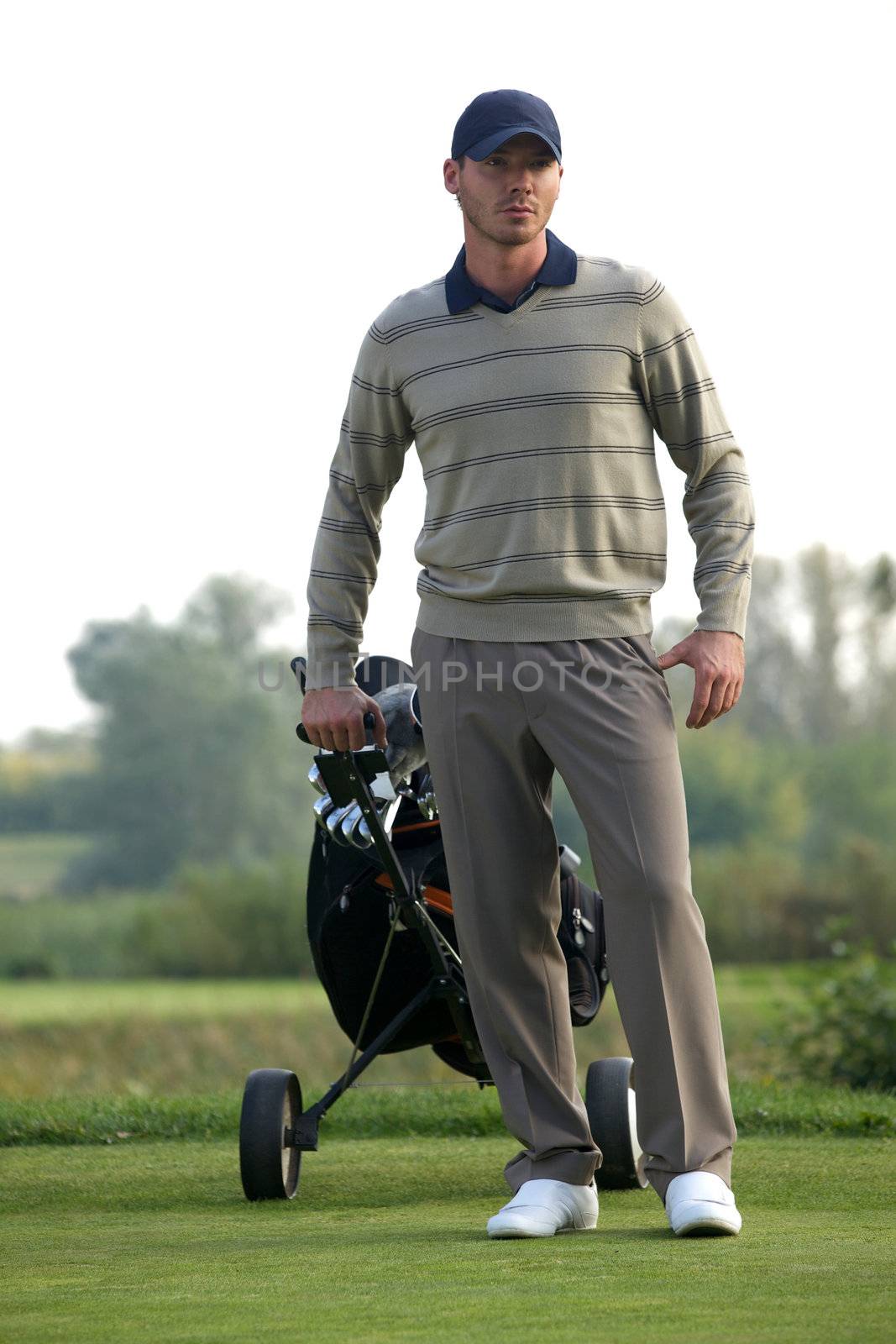 Young man carrying trolley with golf bag