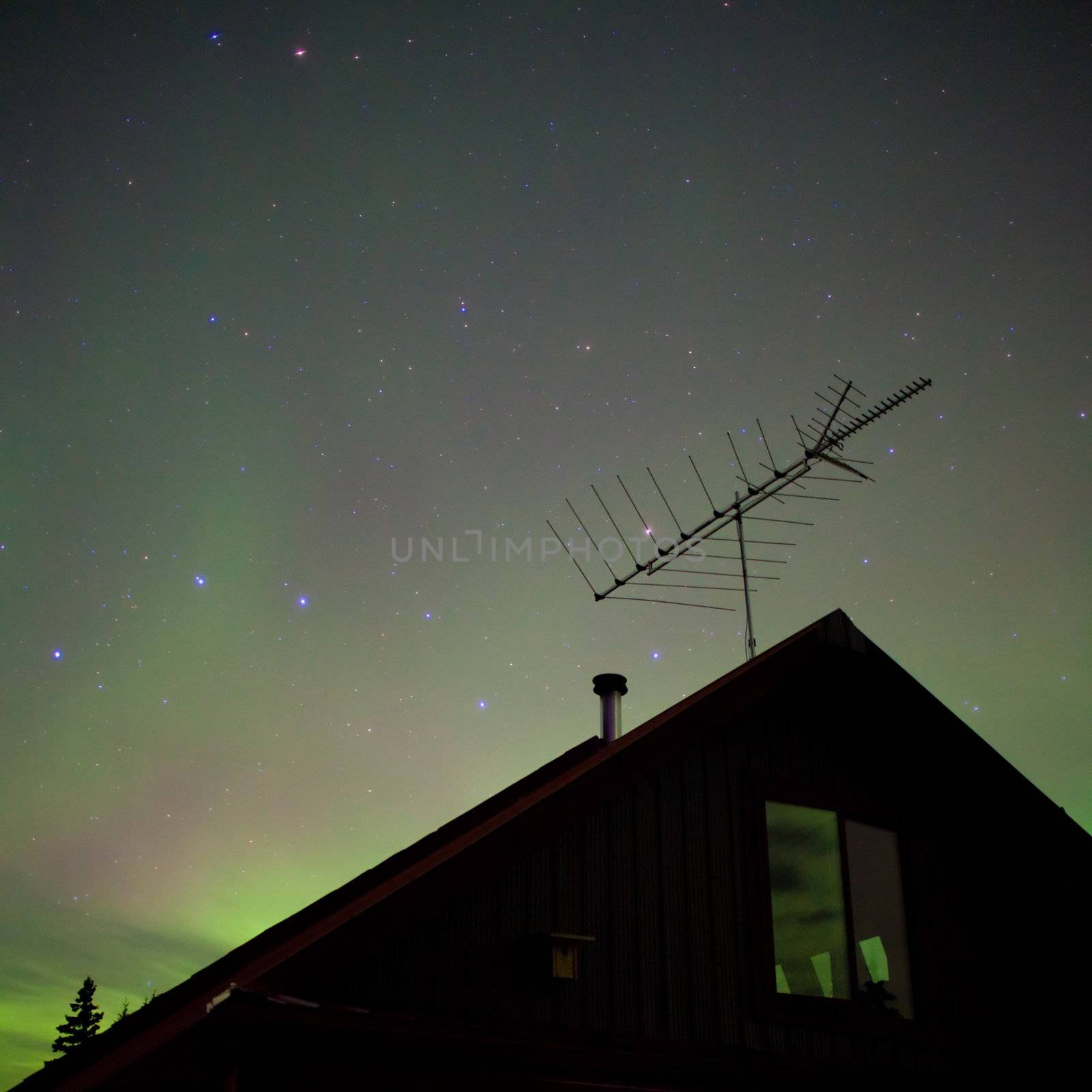 Bright northern lights (Aurora borealis) above house in northern Canada.