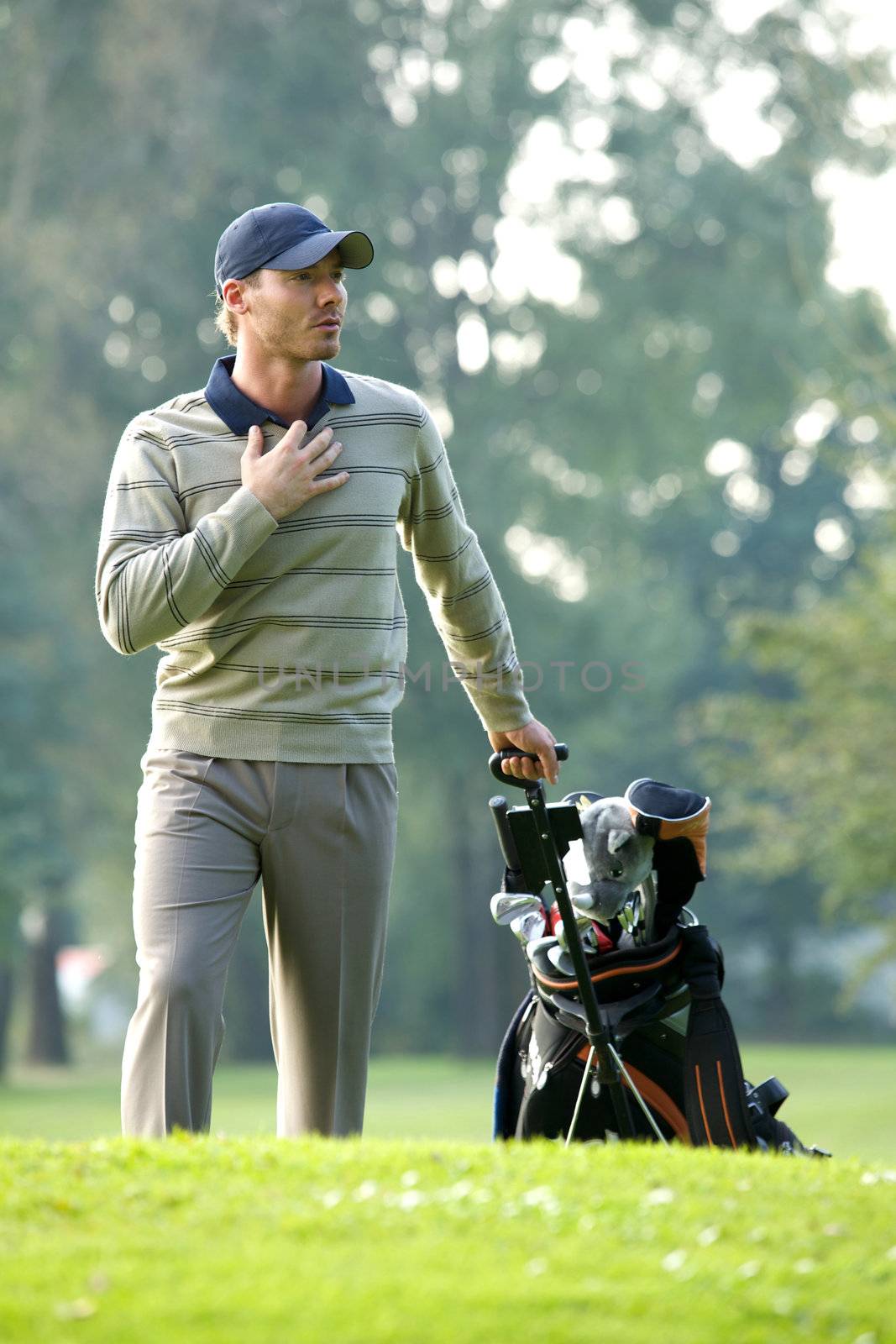 Young man carrying trolley with golf bag