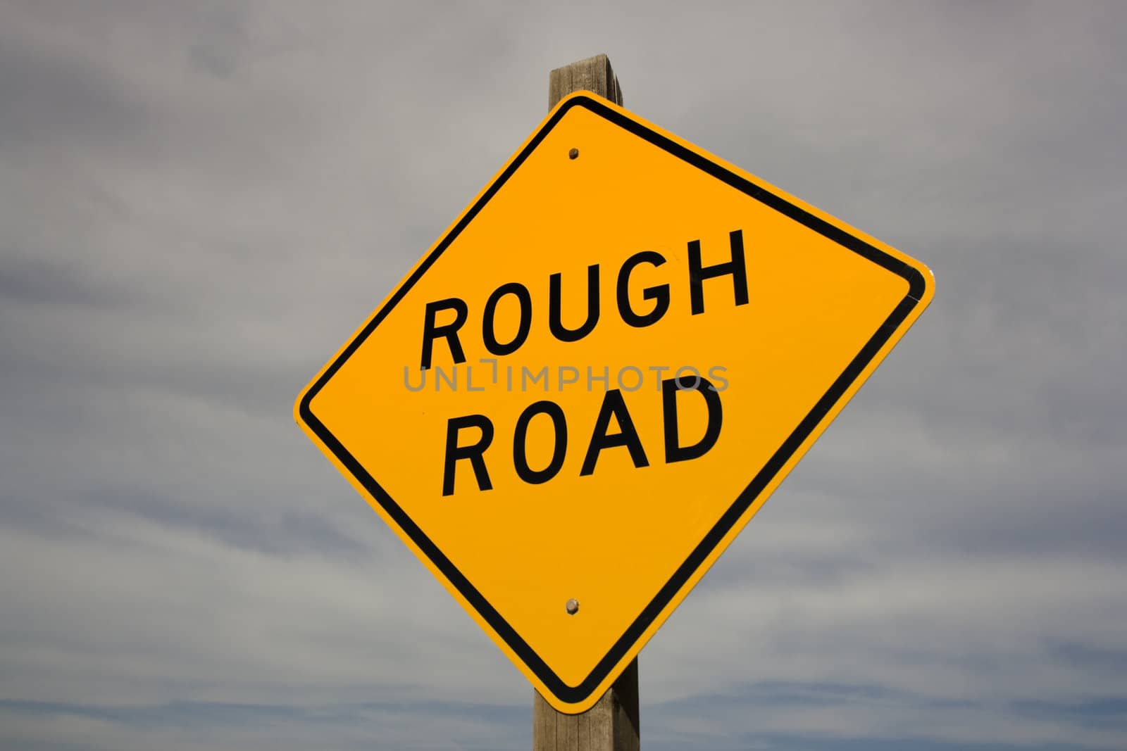 Rough Road sign and cloudy sky.