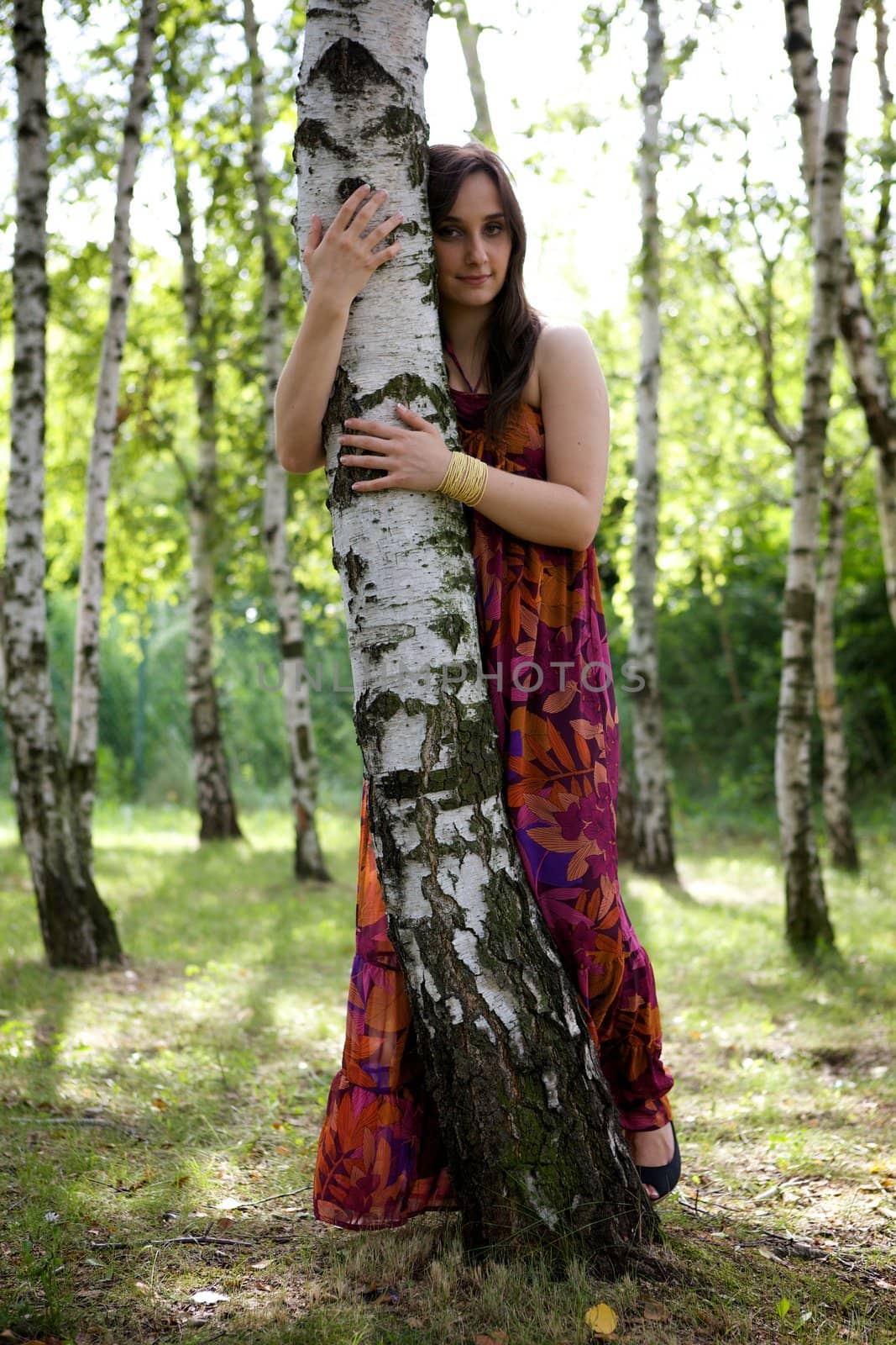 Portrait of young woman hugging tree in park