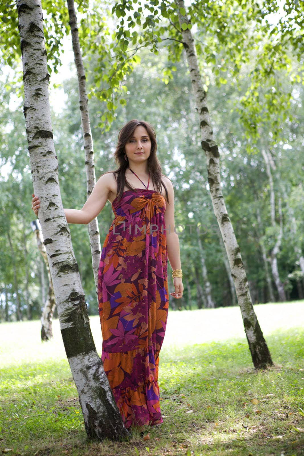 Portrait of young woman standing in park by tree trunk