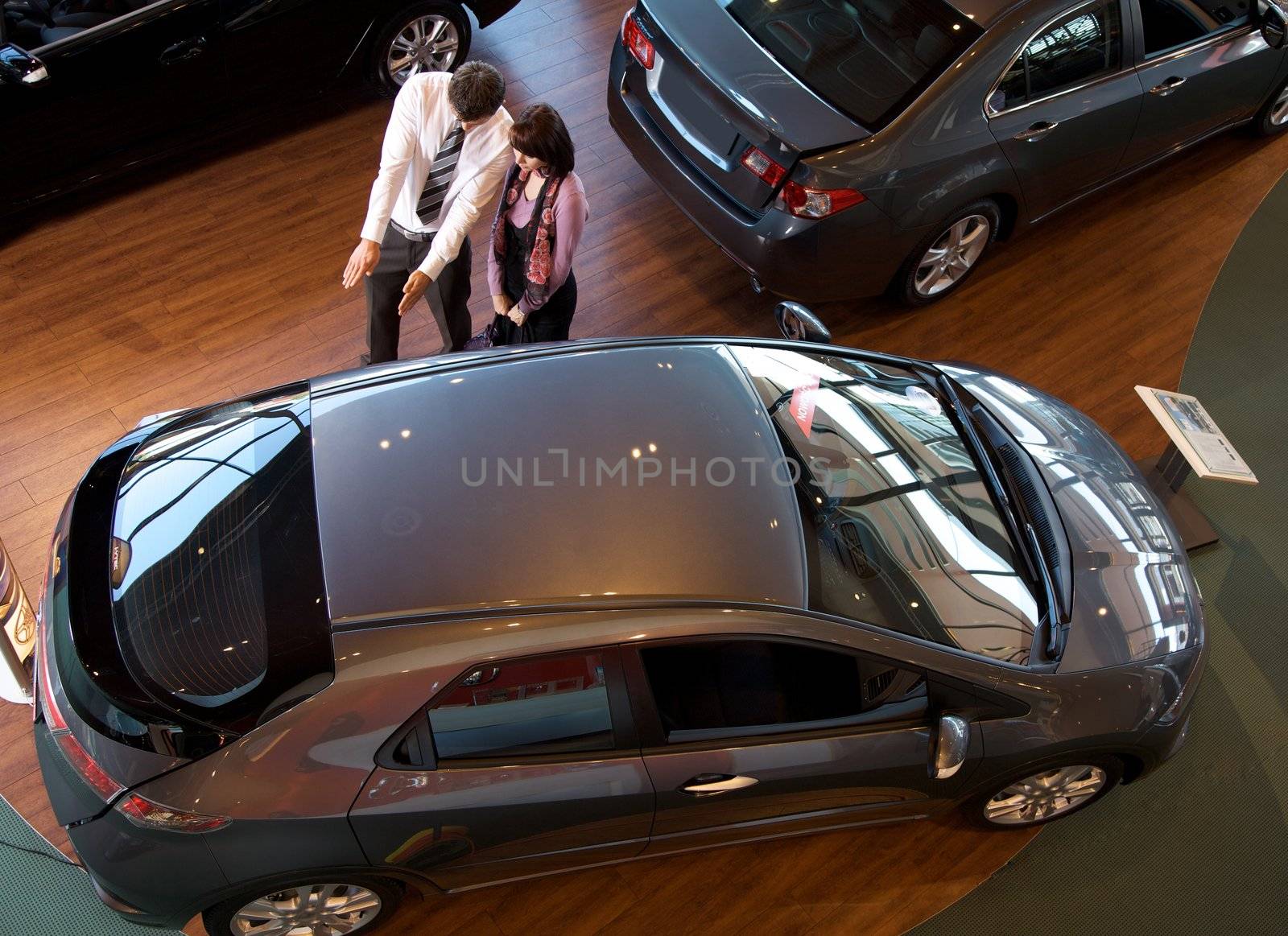 Elevated view of car salesman explaining car features to customer