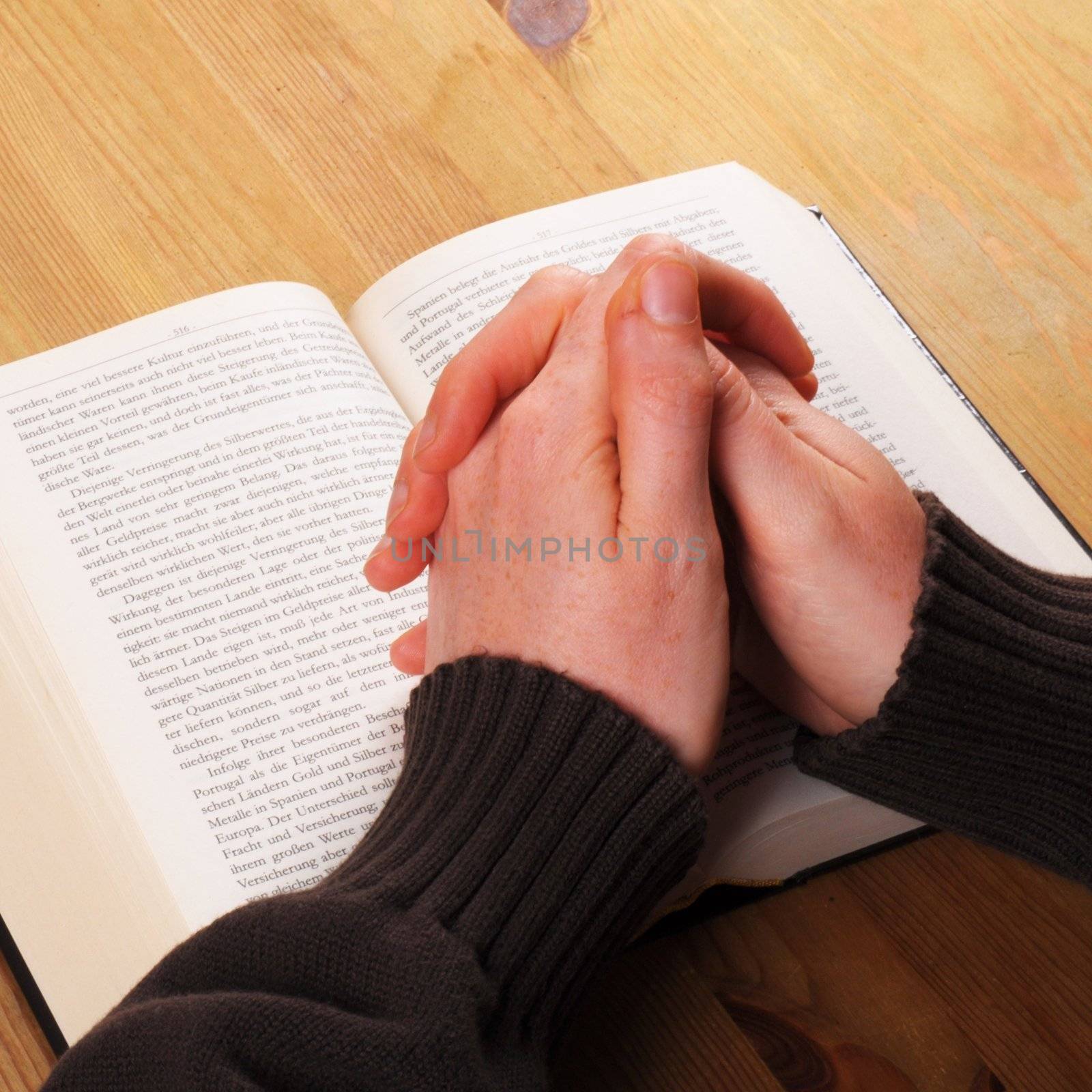 praying hand and book on desk showing religion concept