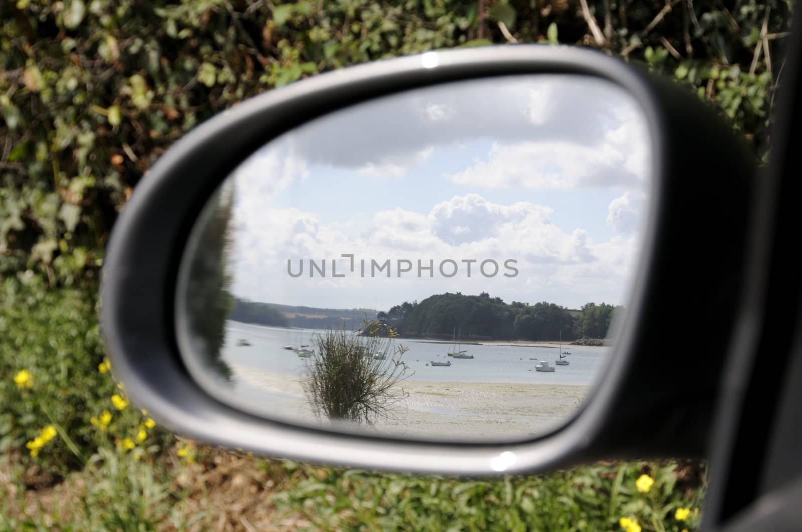 Side mirror of car reflecting beautiful beach in france.