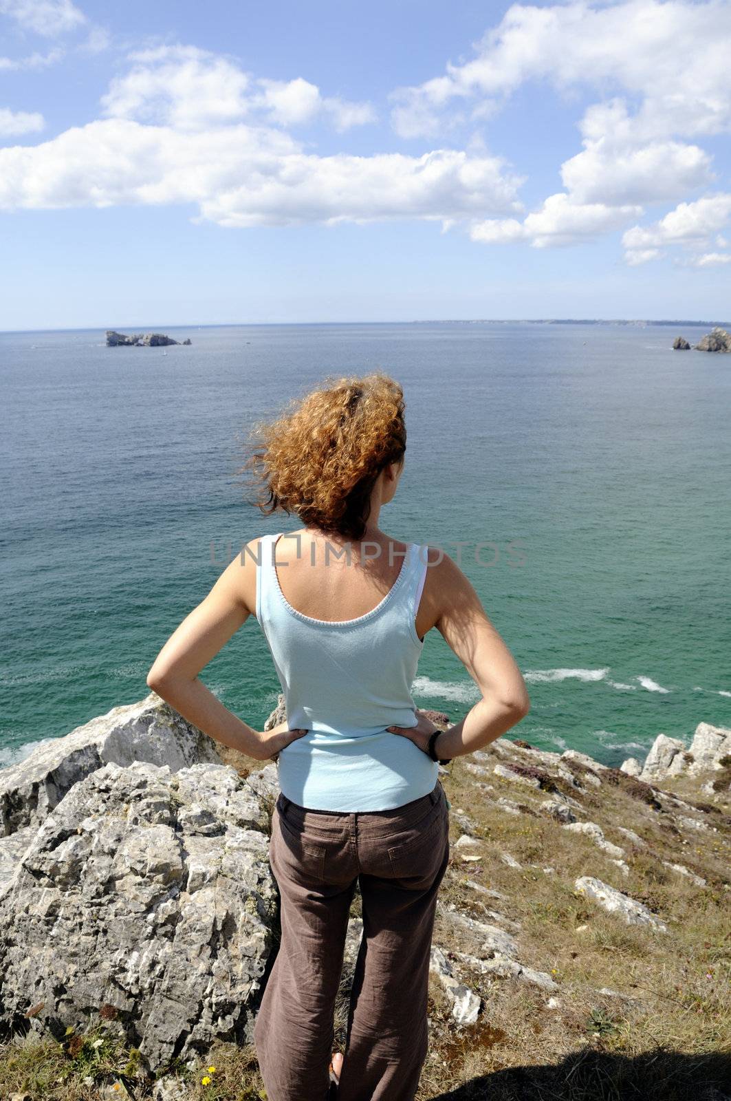 Young woman watching the coastline of the atlantic ocean in Brittany, France