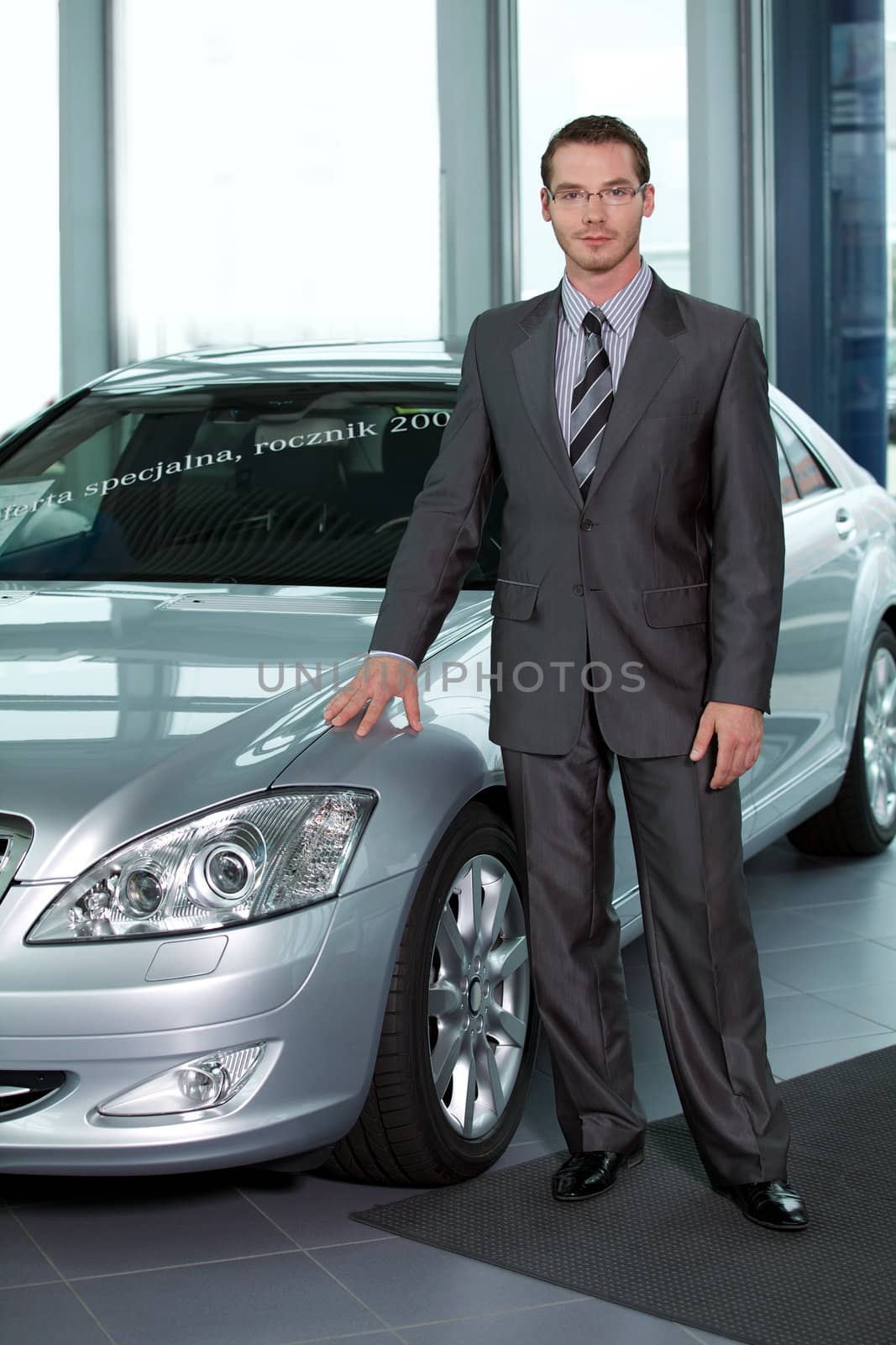 Portrait of car salesperson standing in car showroom