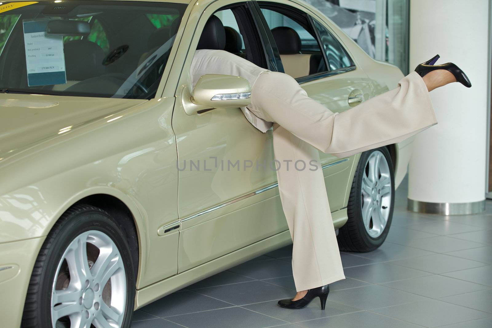 Excited female customer examining interior of new car in showroom
