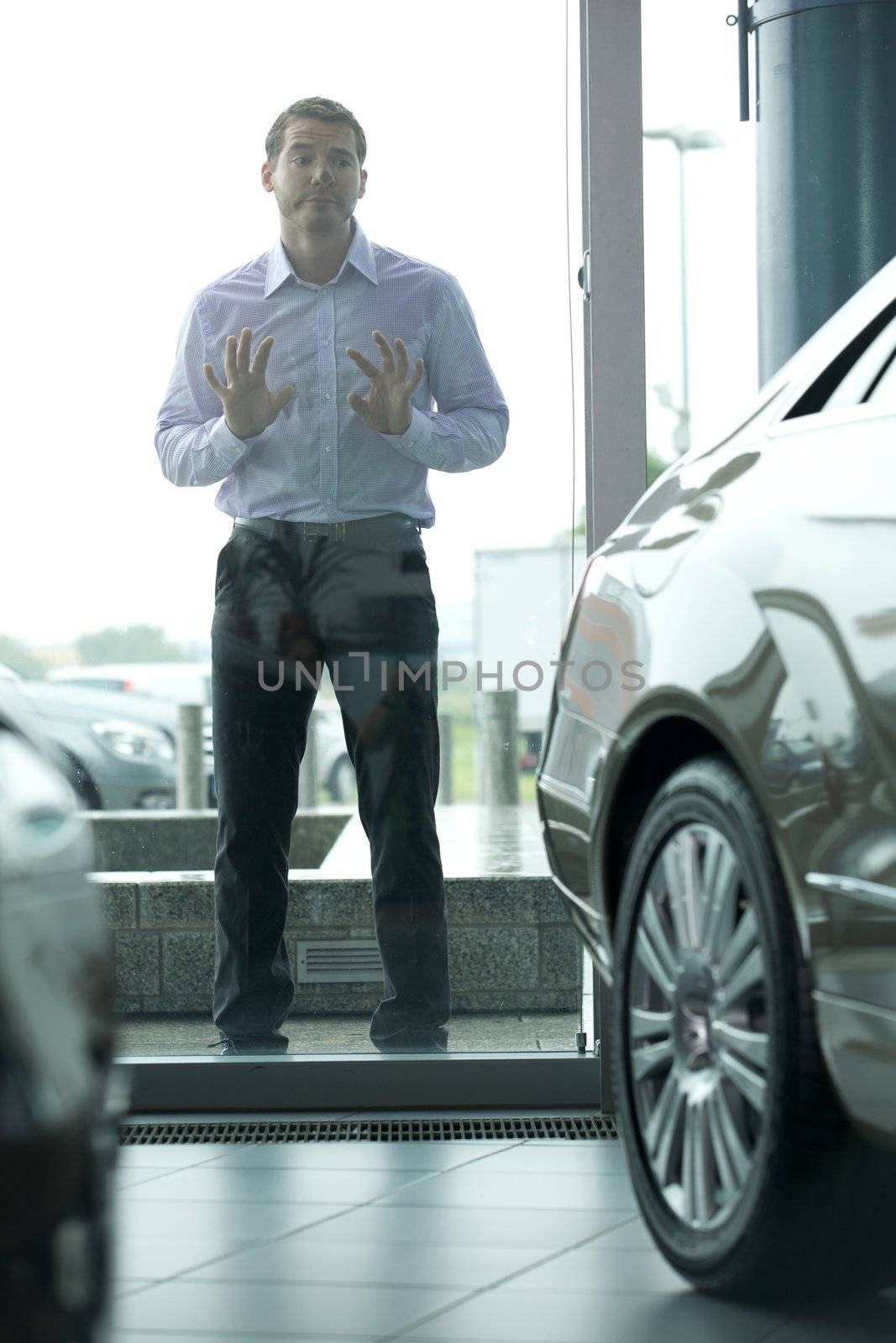 Young man curiously looking at new car in showroom