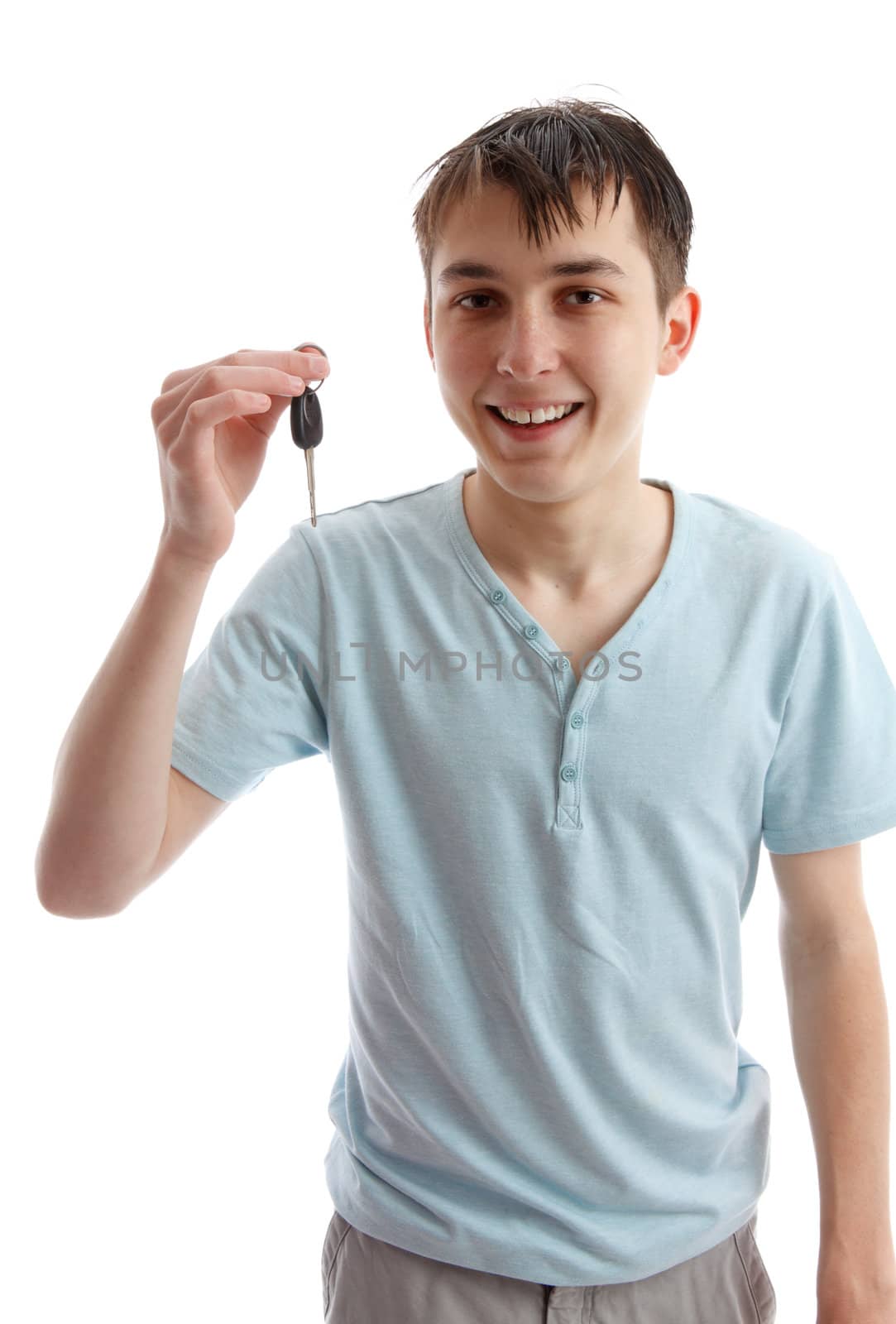 A happy teenager boy holding a car key.  White background.