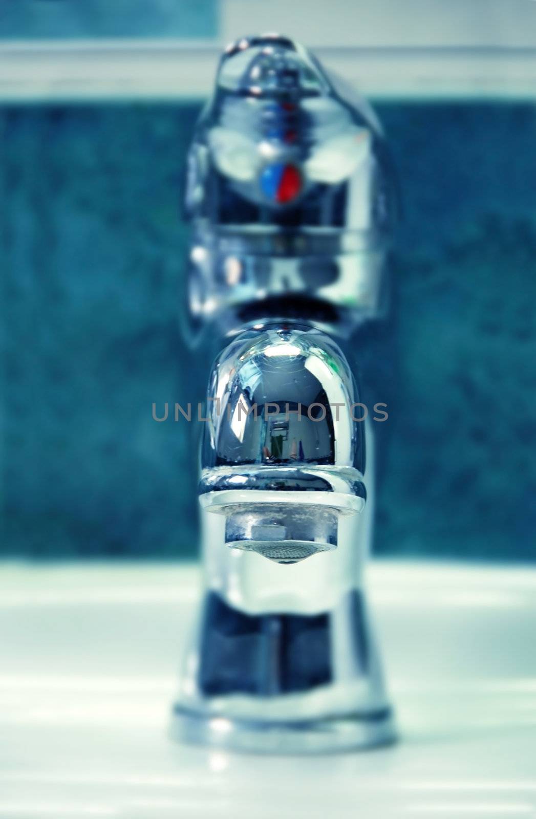 metallic water tap with hanging drop closeup